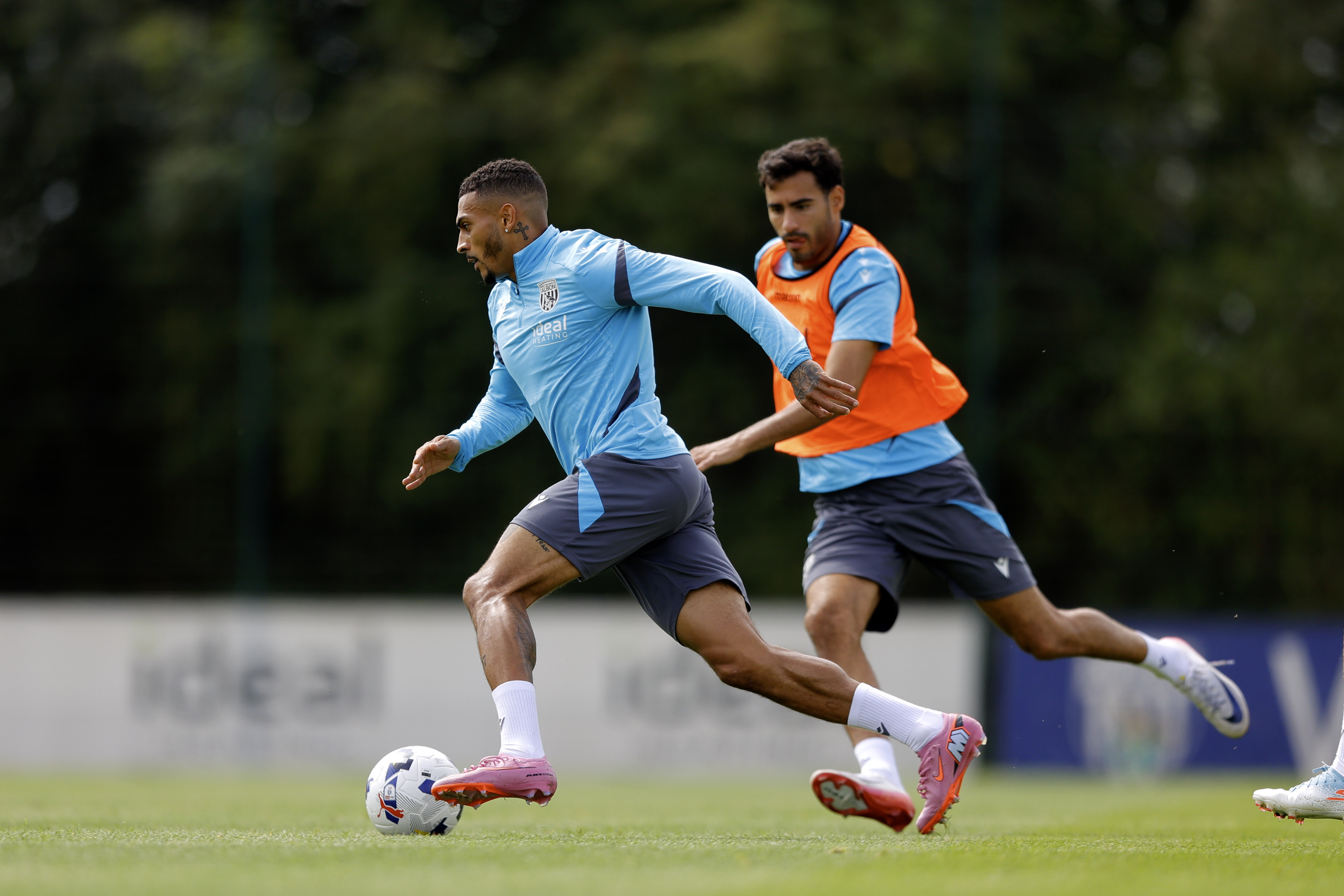 Karlan Grant running with the ball during training, chased by Gianluca Frabotta 