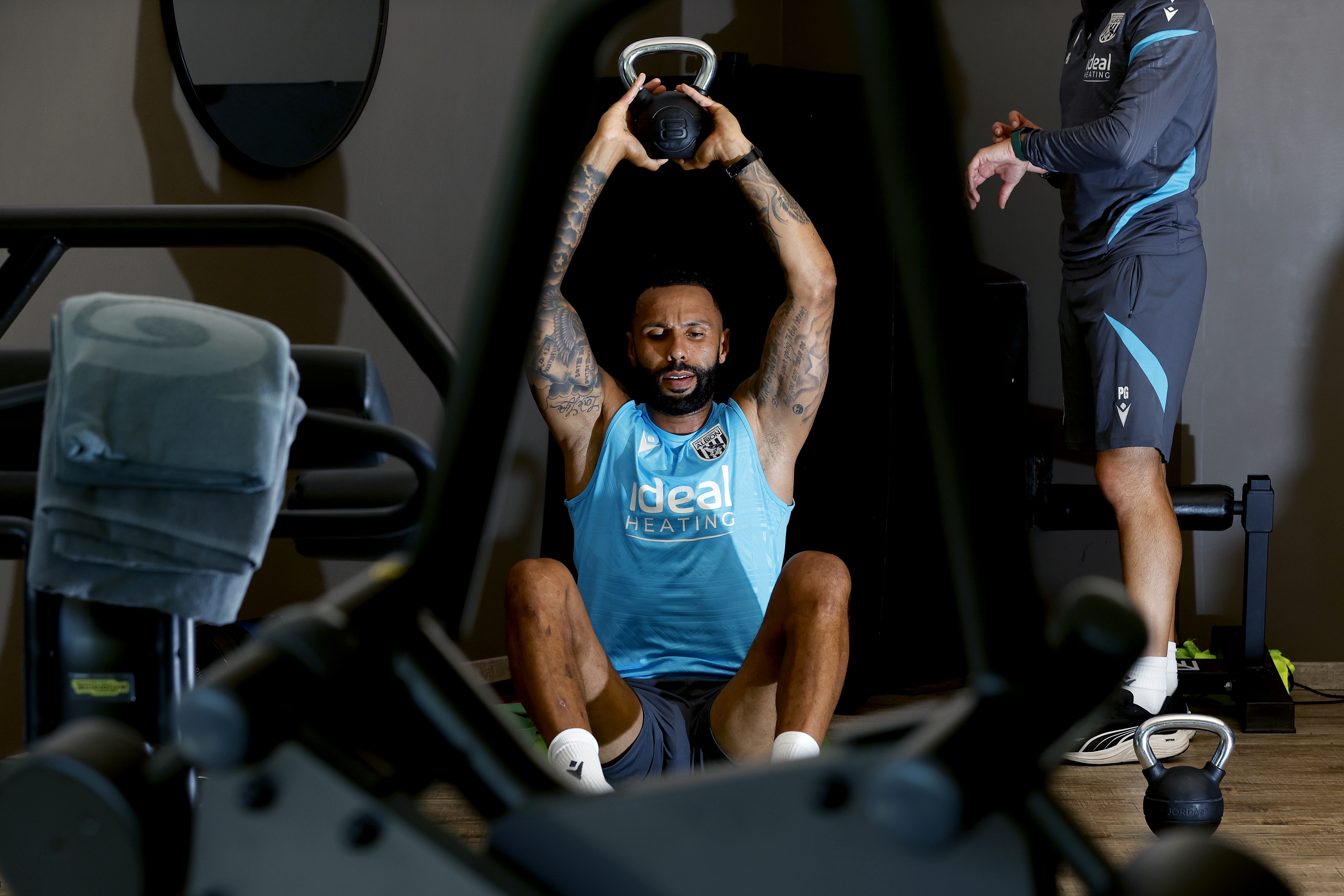 Kyle Bartley sat in the gym with a kettlebell weight above his head