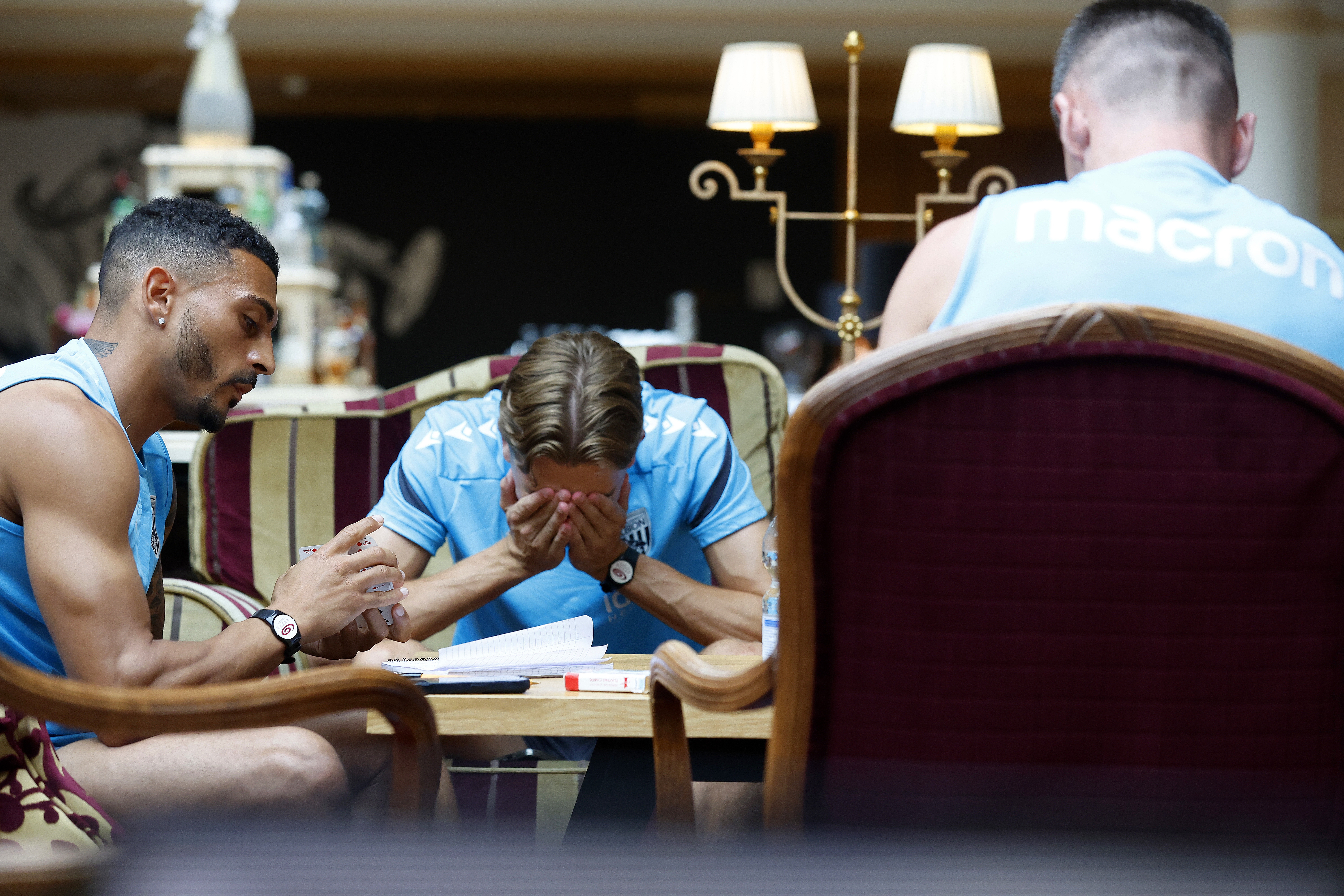 Several Albion players playing cards with Isaac Price sat with his head in his hands