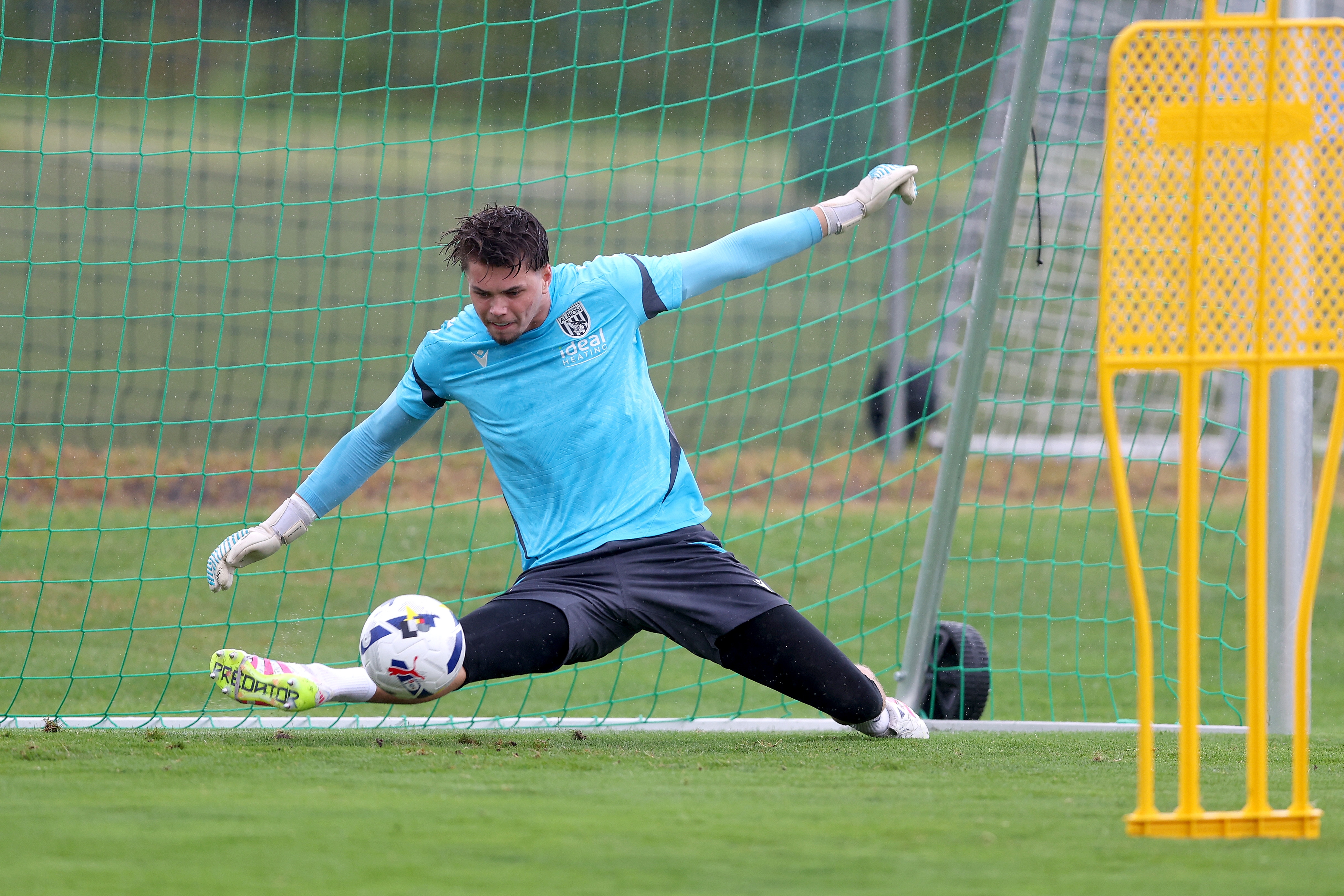 Josh Griffiths saving a shot with his foot during a training session in the rain