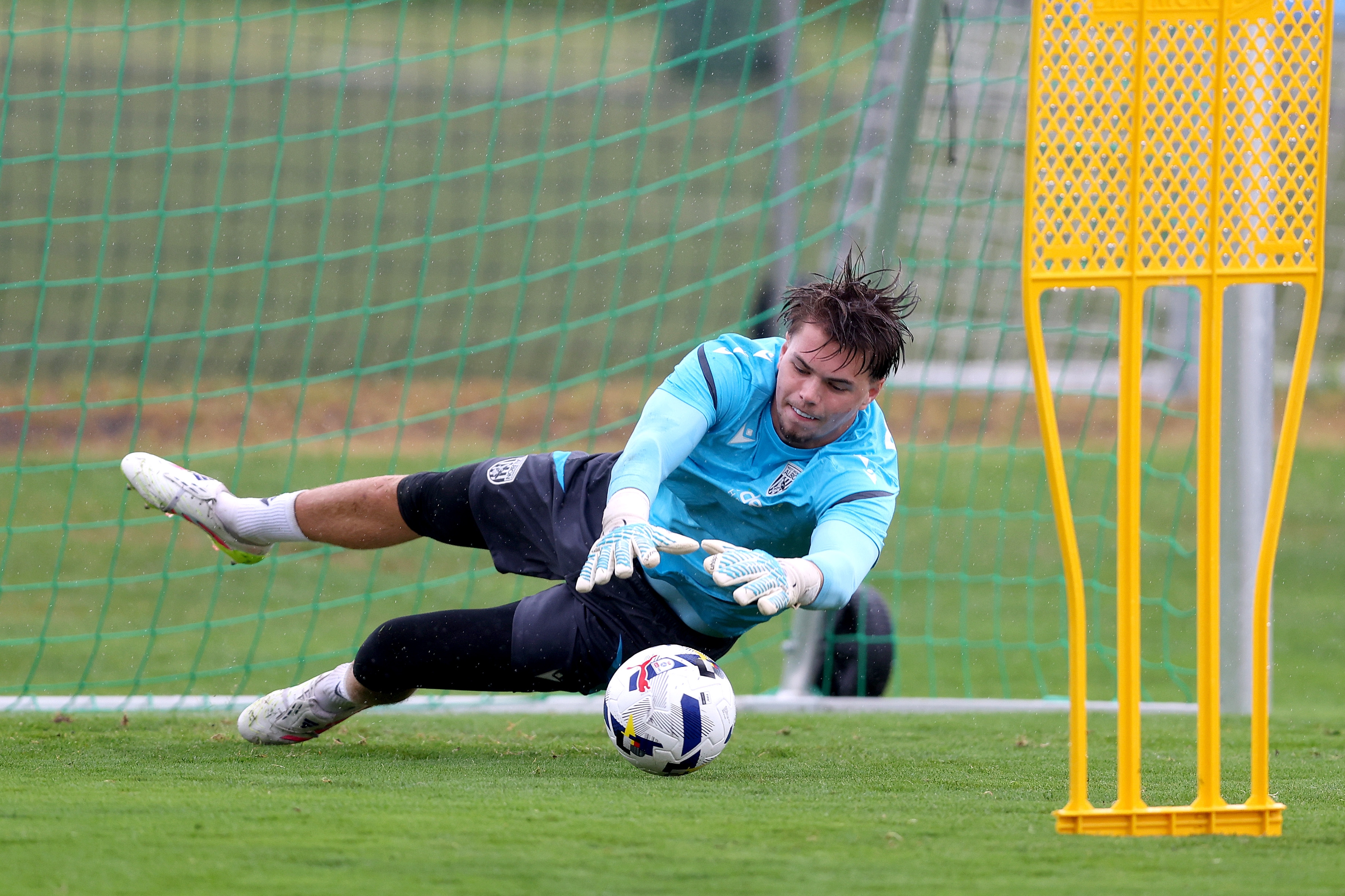 Josh Griffiths saving a shot with his hands during a training session in the rain