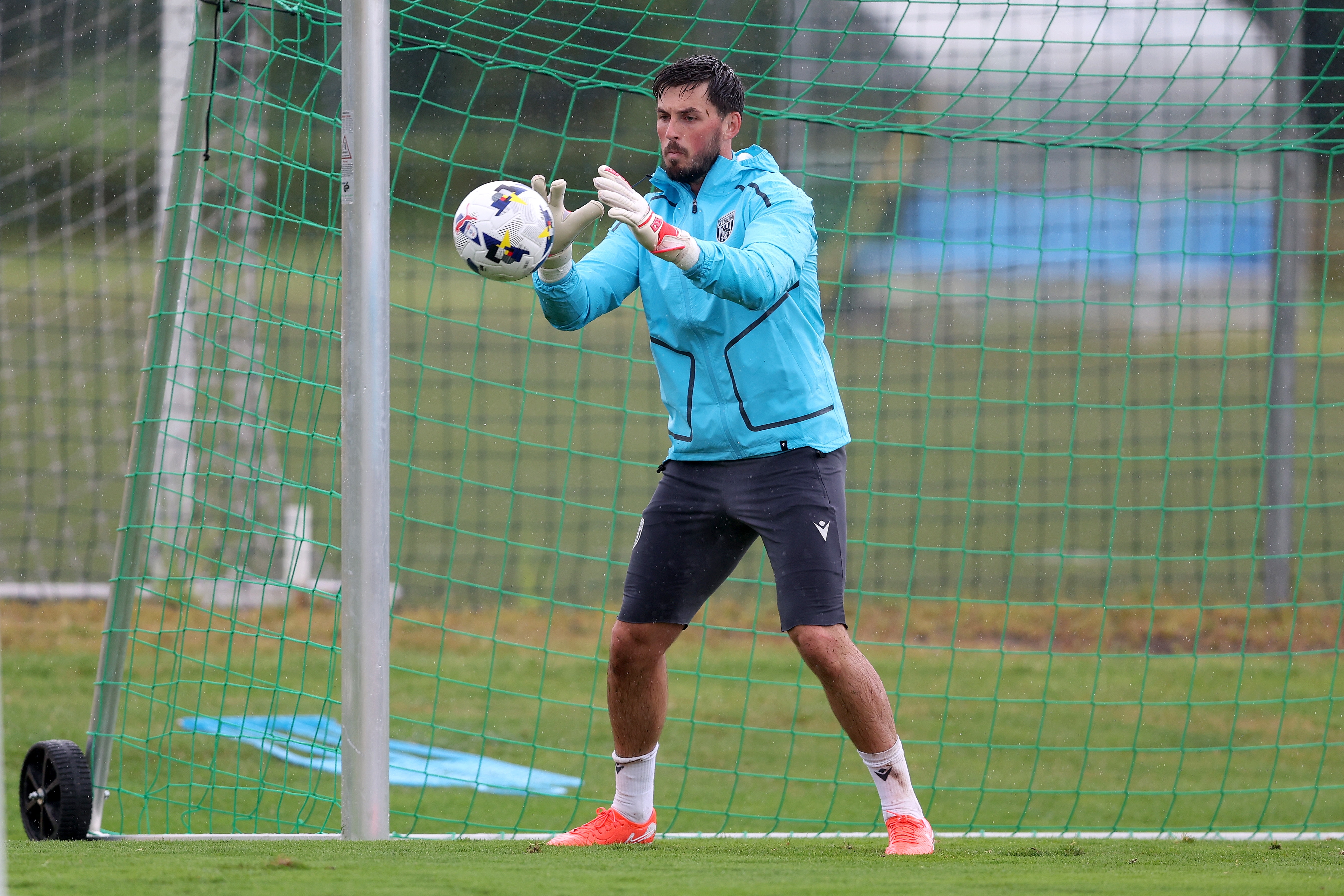 Joe Wildsmith saving a shot with his hands during a training session in the rain