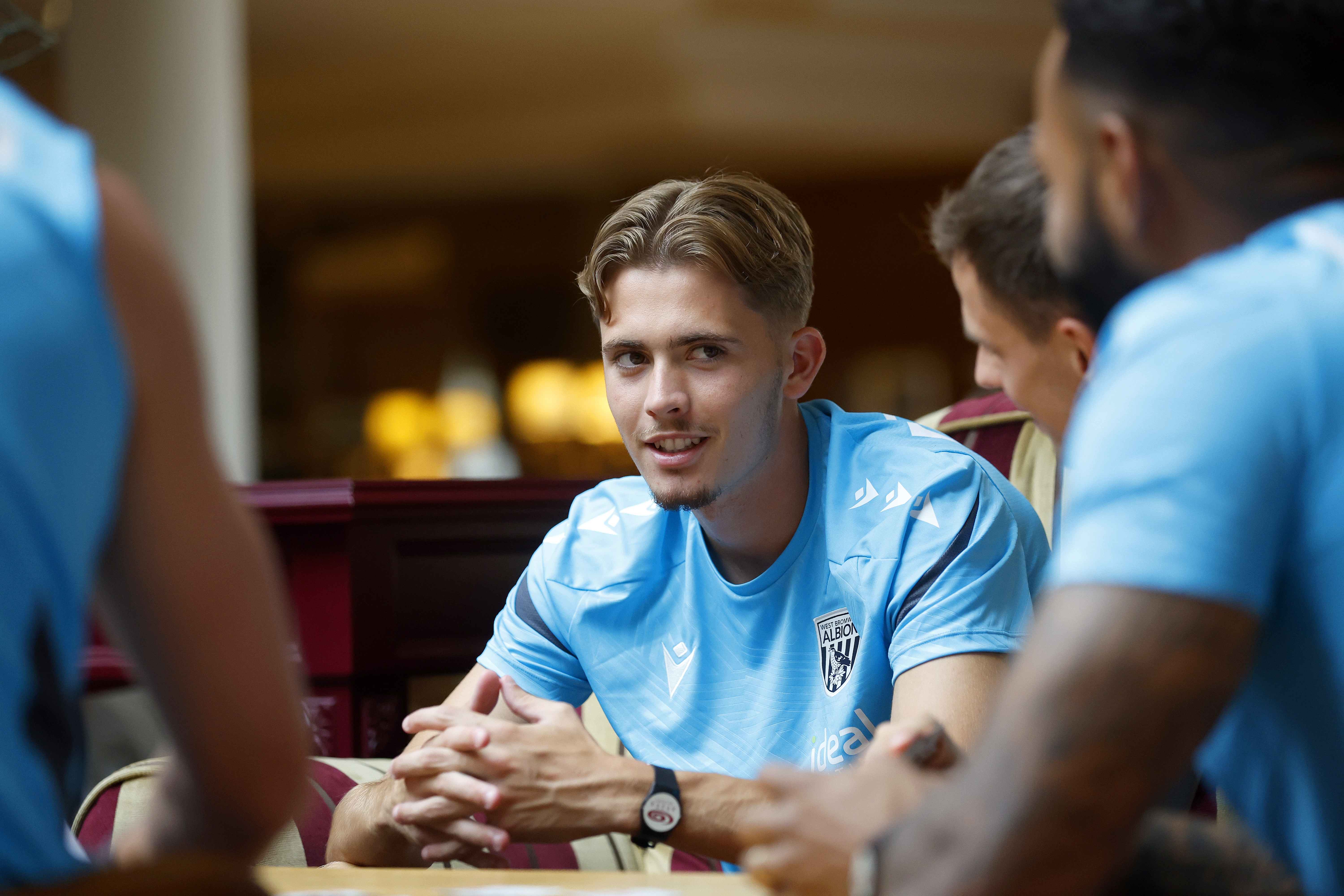 Isaac Price looking at his team-mates while playing cards