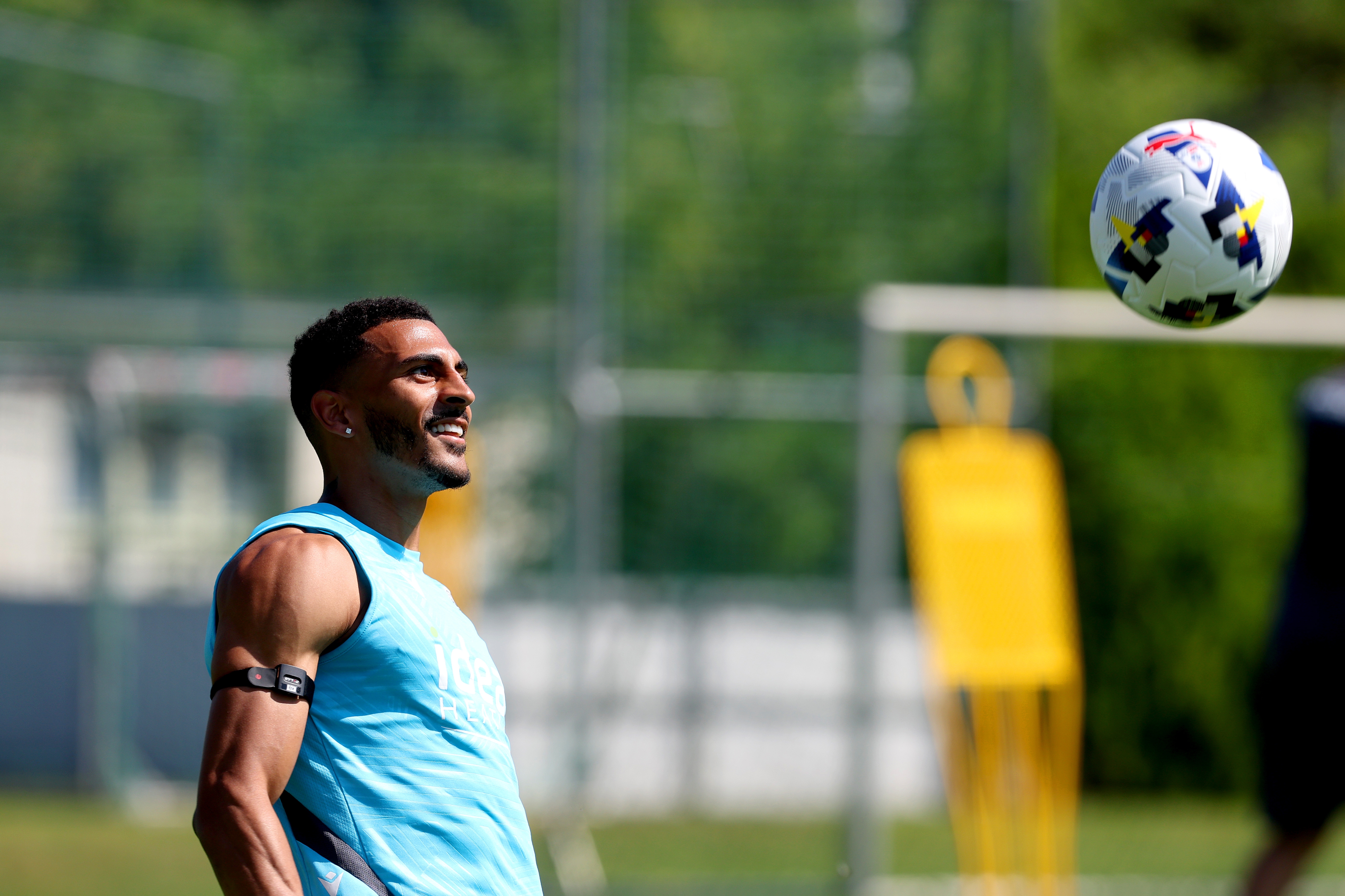 Karlan Grant smiling while keeping his eyes on the ball during a training session