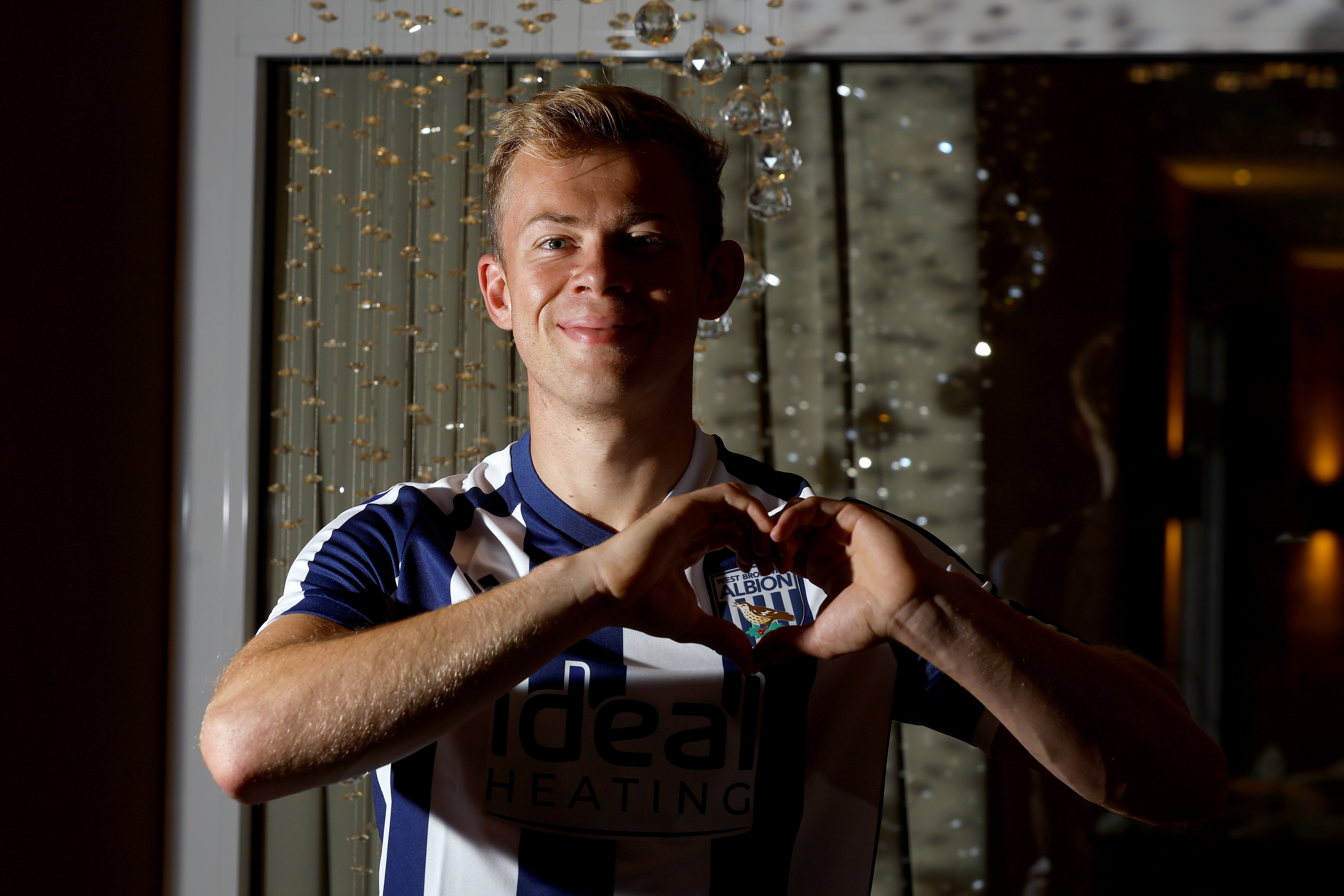 Aune Heggebø smiling at the camera while in a WBA shirt making a heart shape