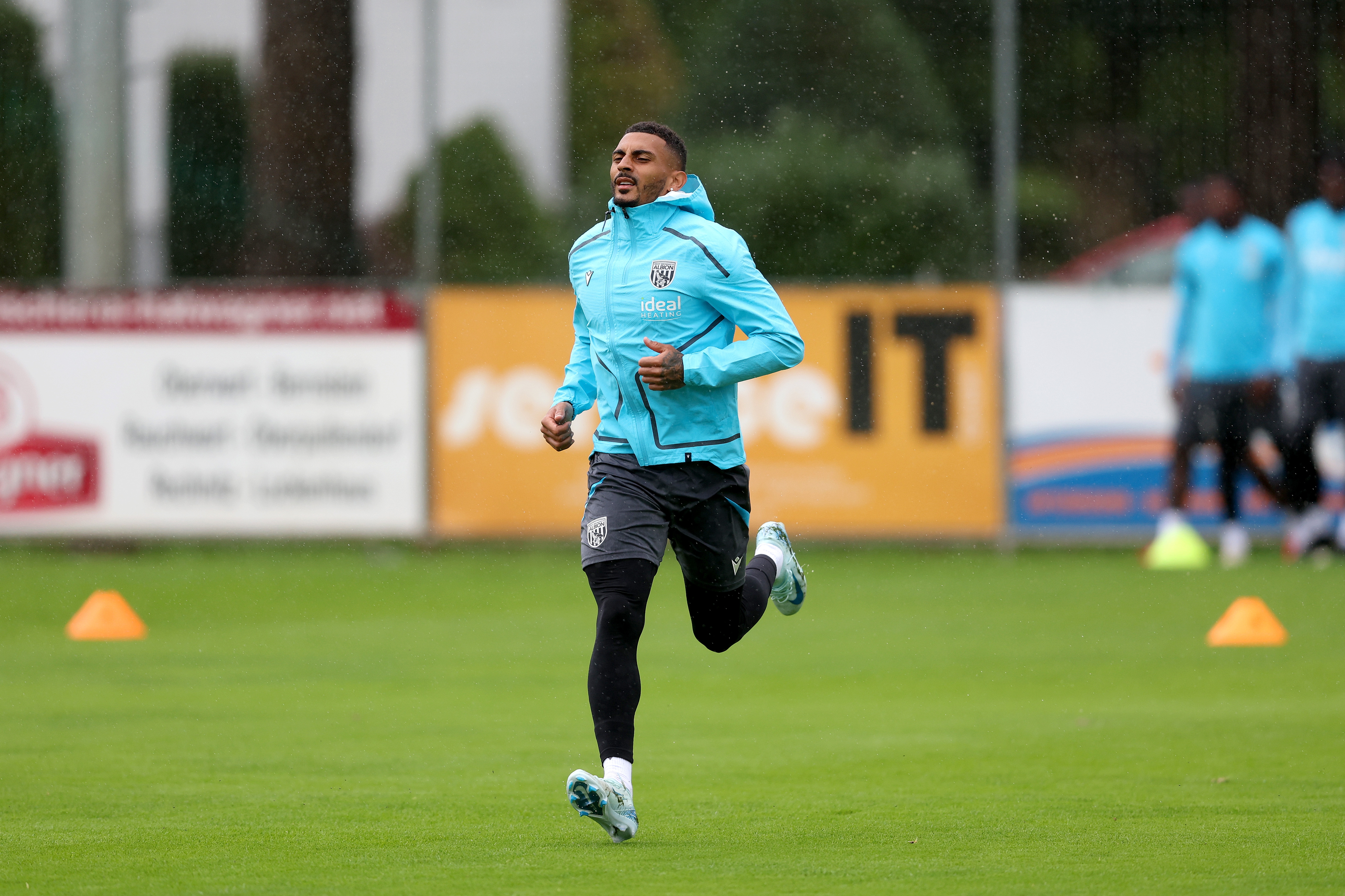 Karlan Grant running forward during a training session in the rain
