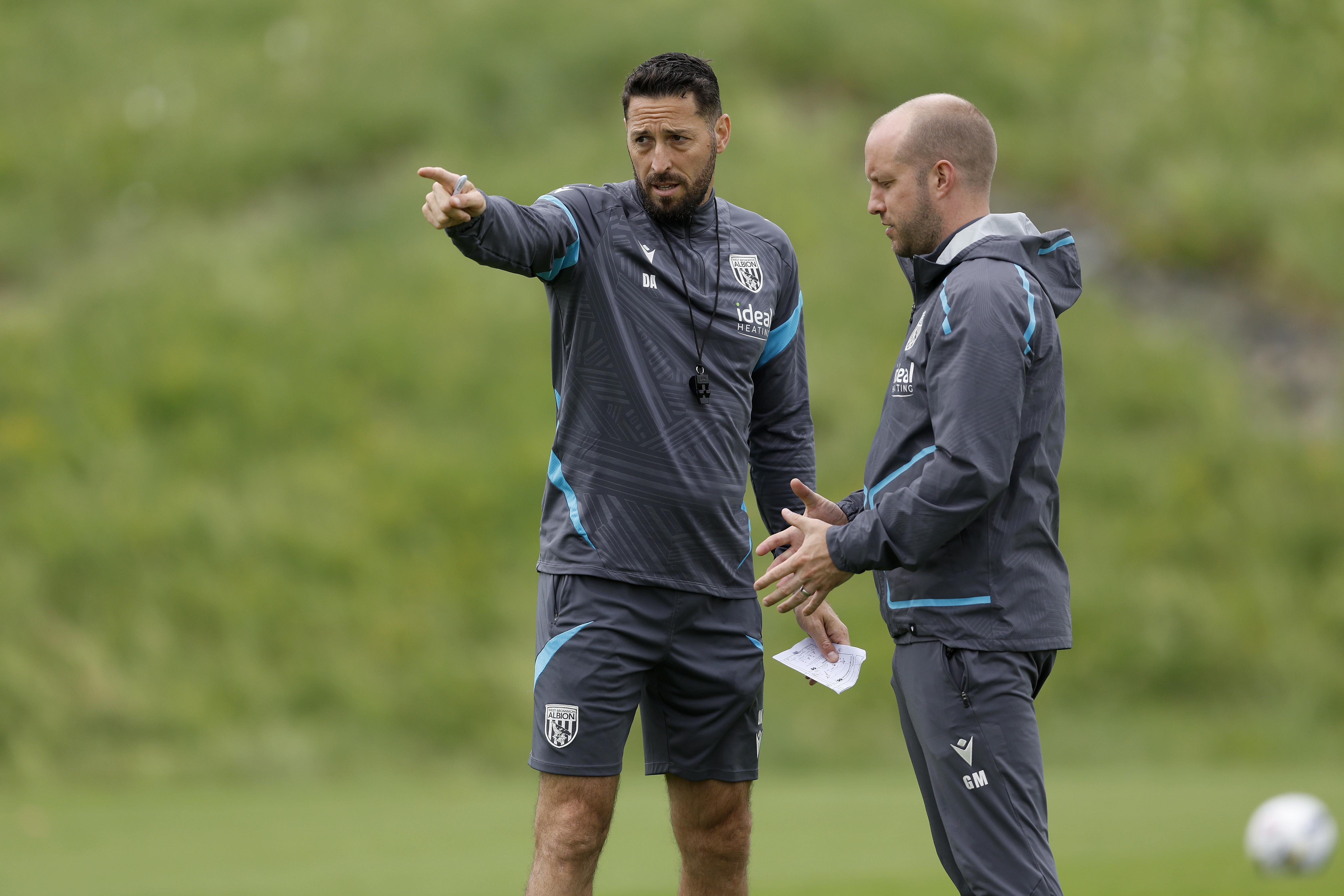 Damia Abella pointing forward while talking to a member of staff on the training pitch