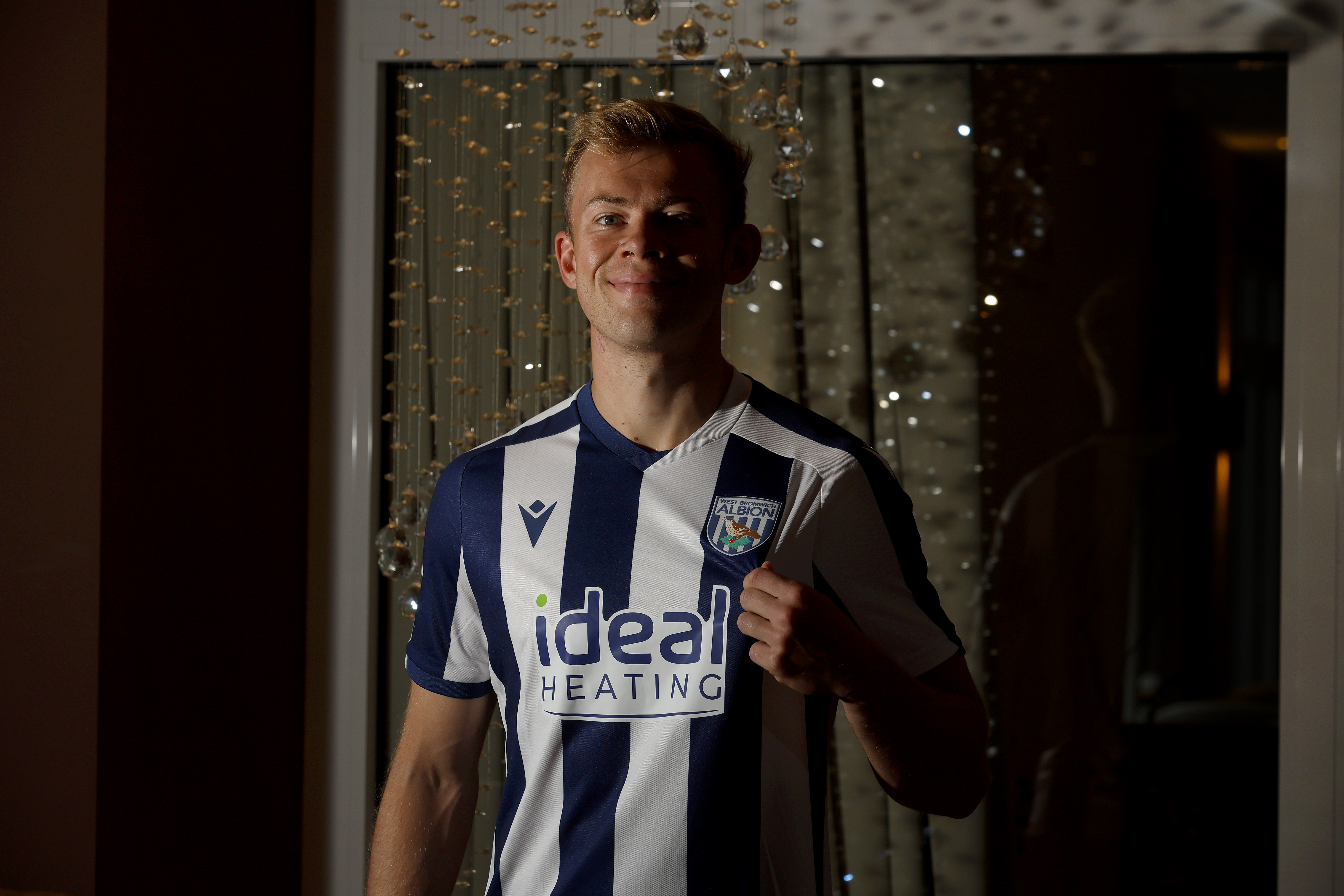 Aune Heggebø smiling at the camera while in a WBA shirt pulling on the badge