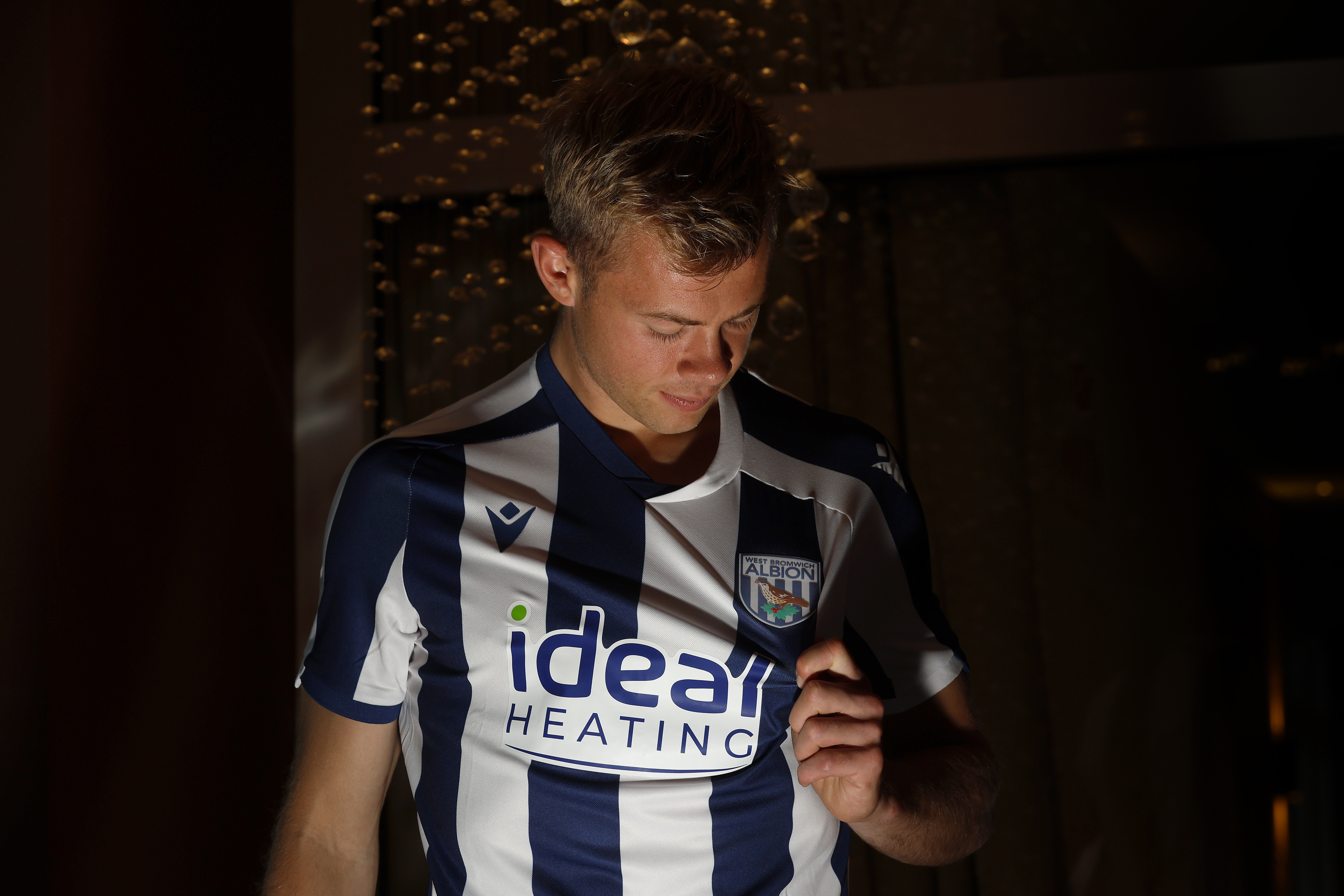 Aune Heggebø pulling the badge and looking at it while wearing a WBA shirt
