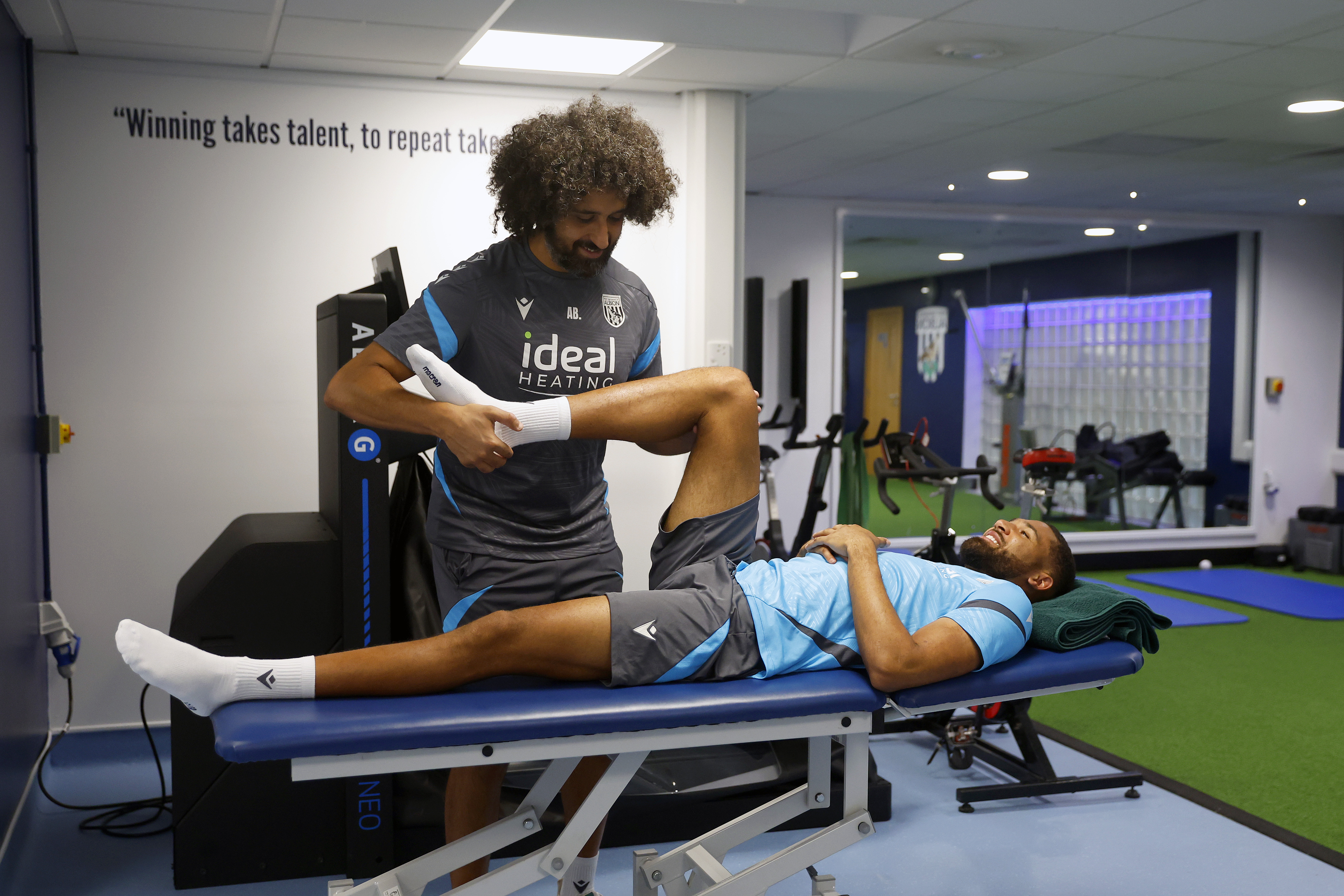 George Campbell laying on a medical bed stretching with a WBA physio 