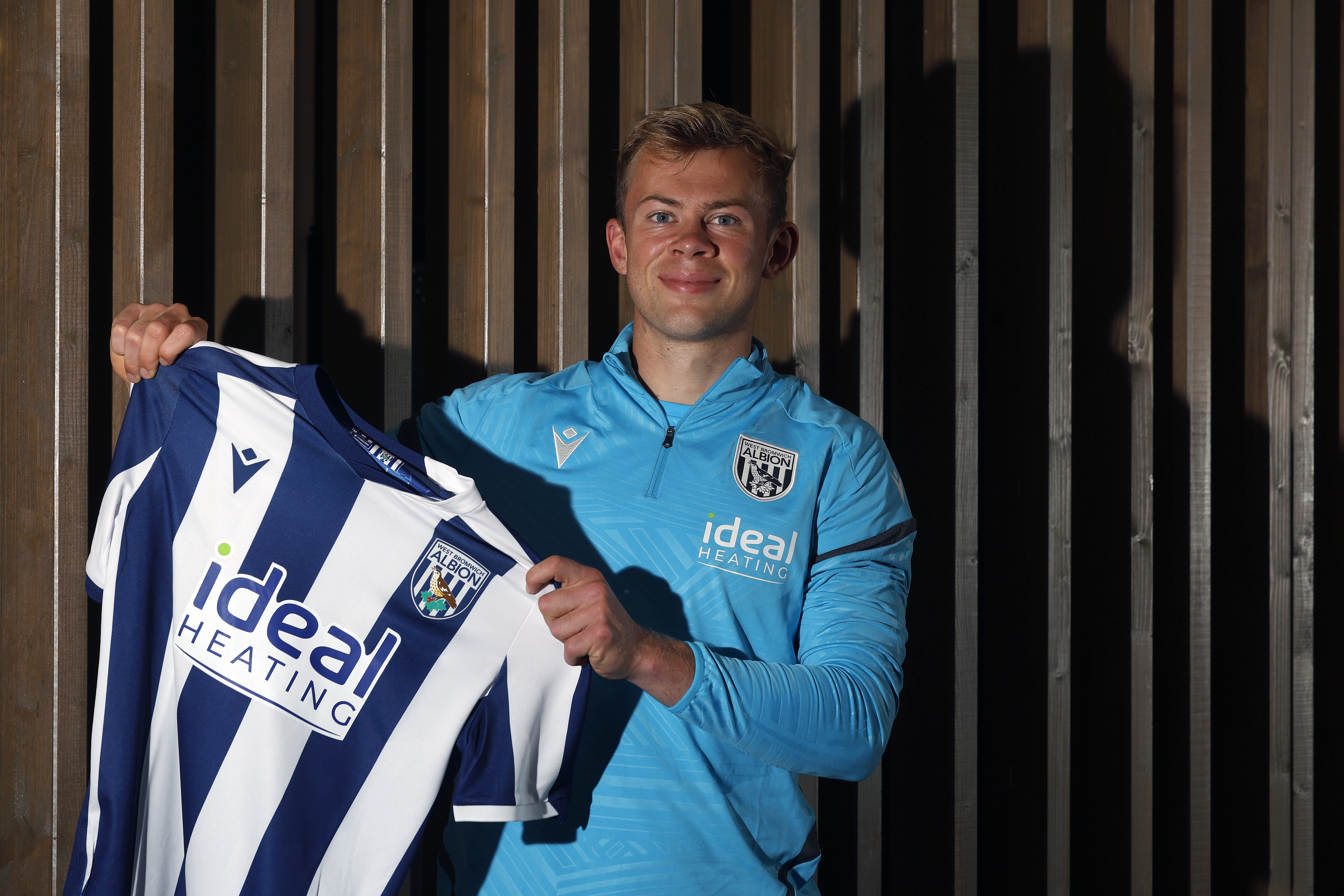 Aune Heggebø smiling at the camera and holding up a home shirt