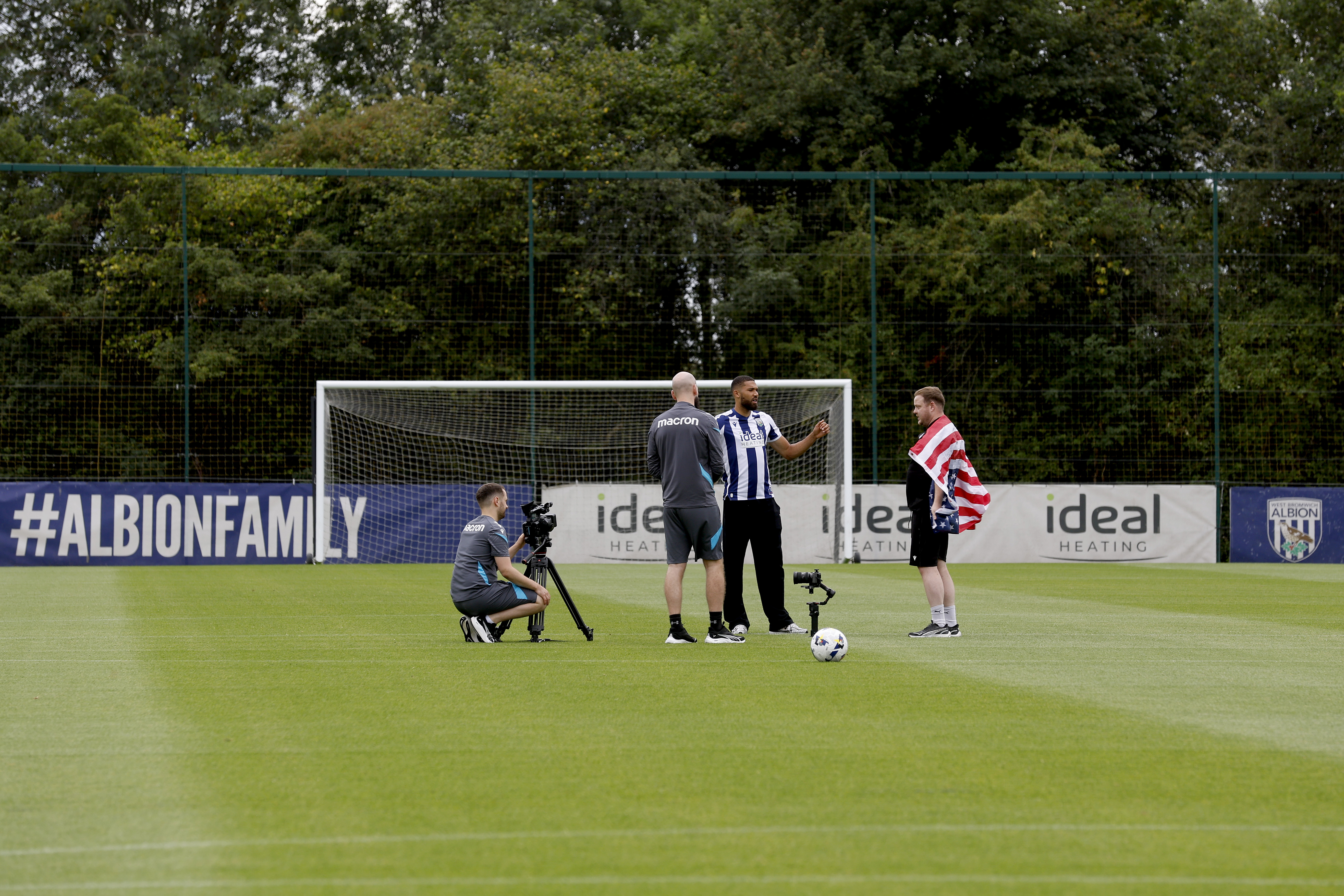 George Campbell is surrounded by WBA media staff in the middle of a training pitch 