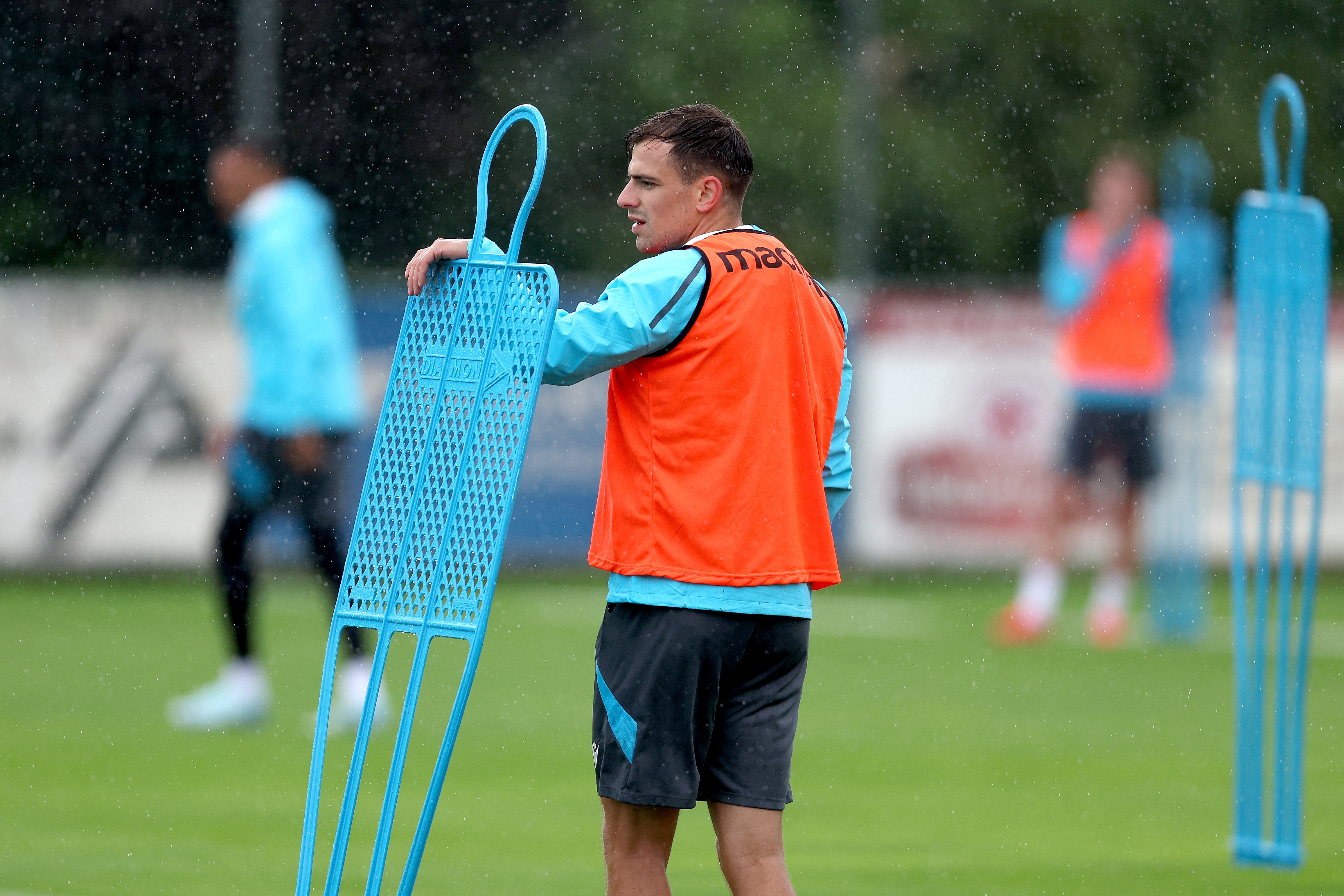 Jayson Molumby looking over a mannequin during a training session in the rain