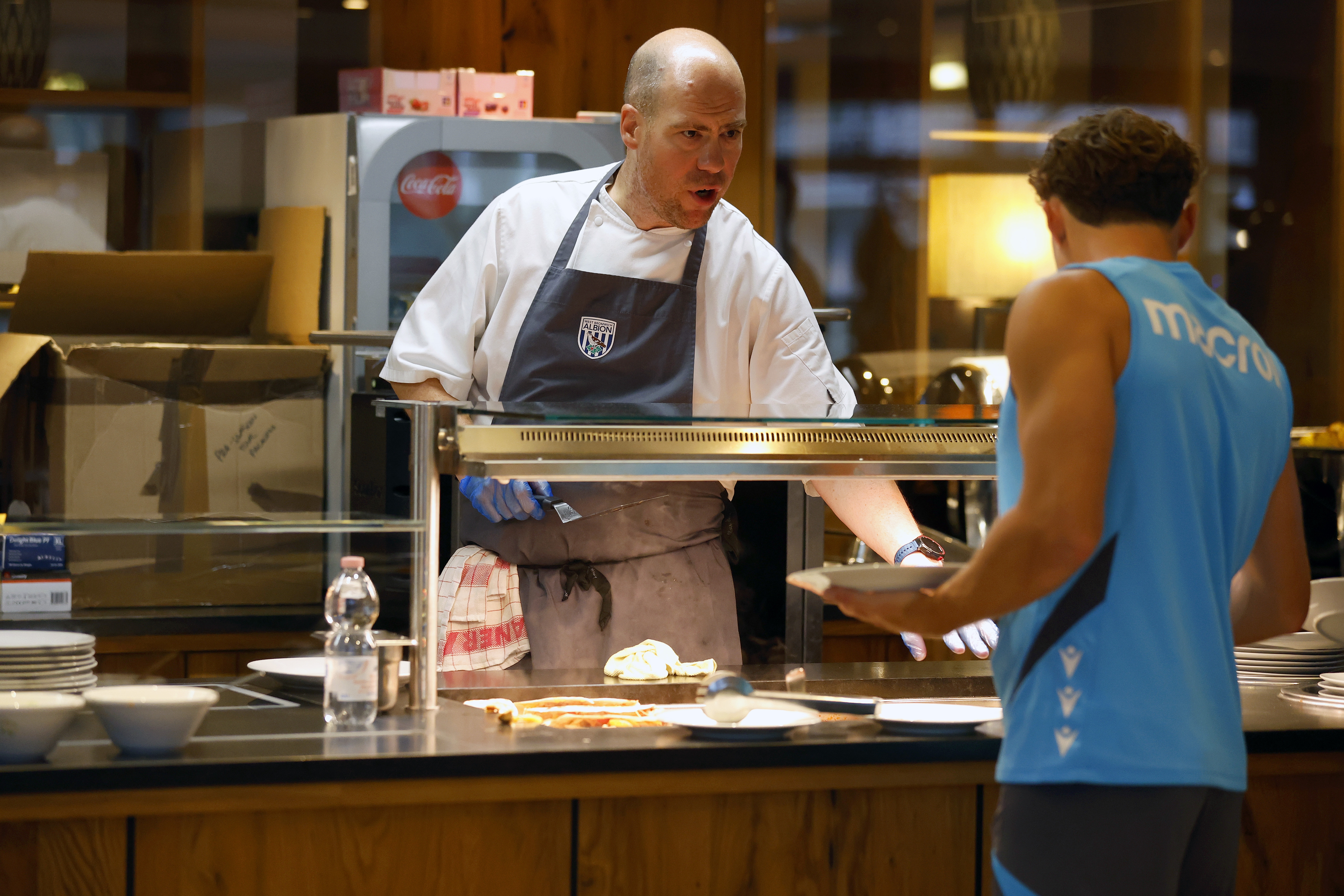 A WBA chef preparing food for a player at the hotel and talking to him