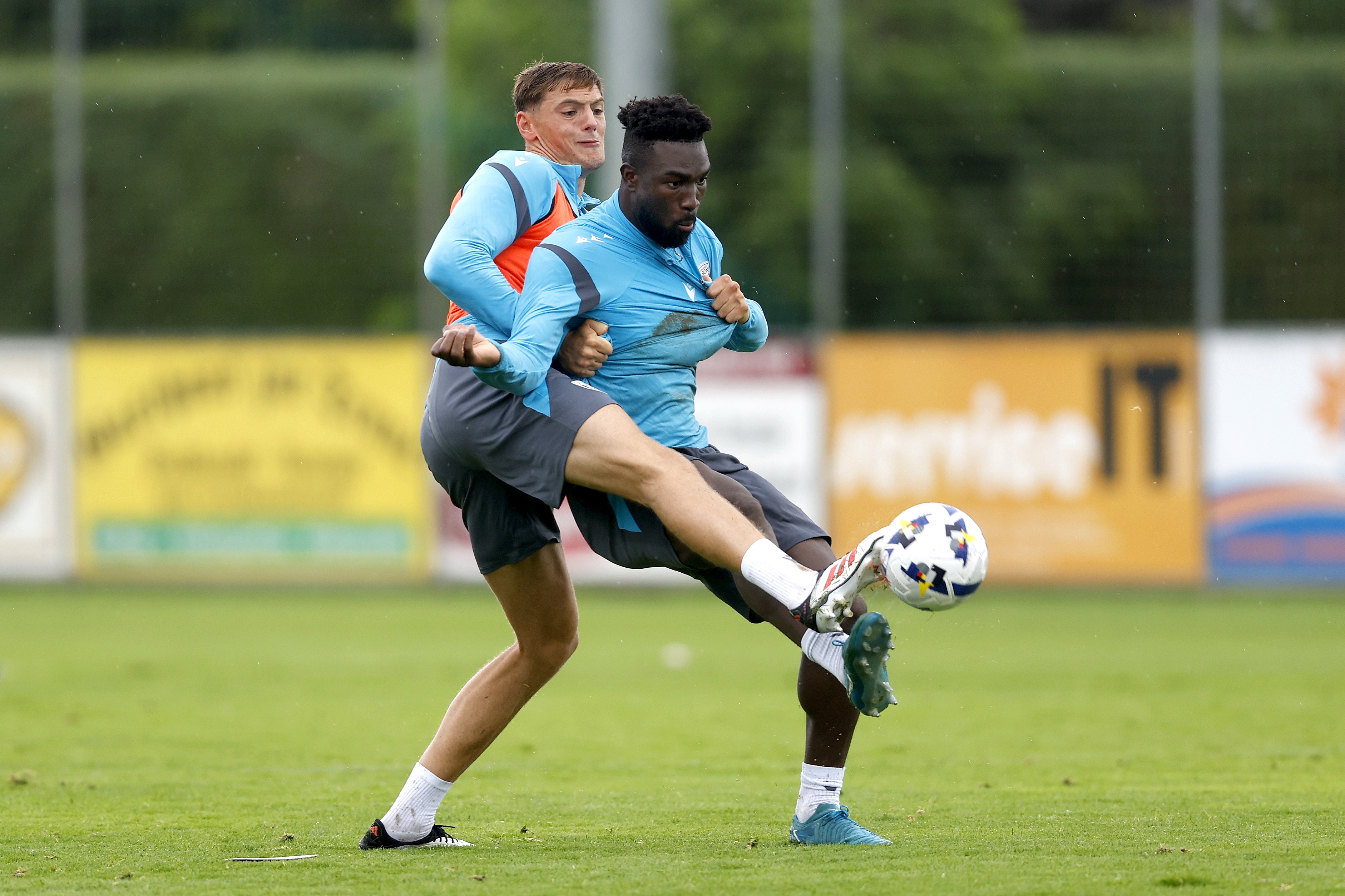 Caleb Taylor and Daryl Dike fighting for the ball during a training session in the rain