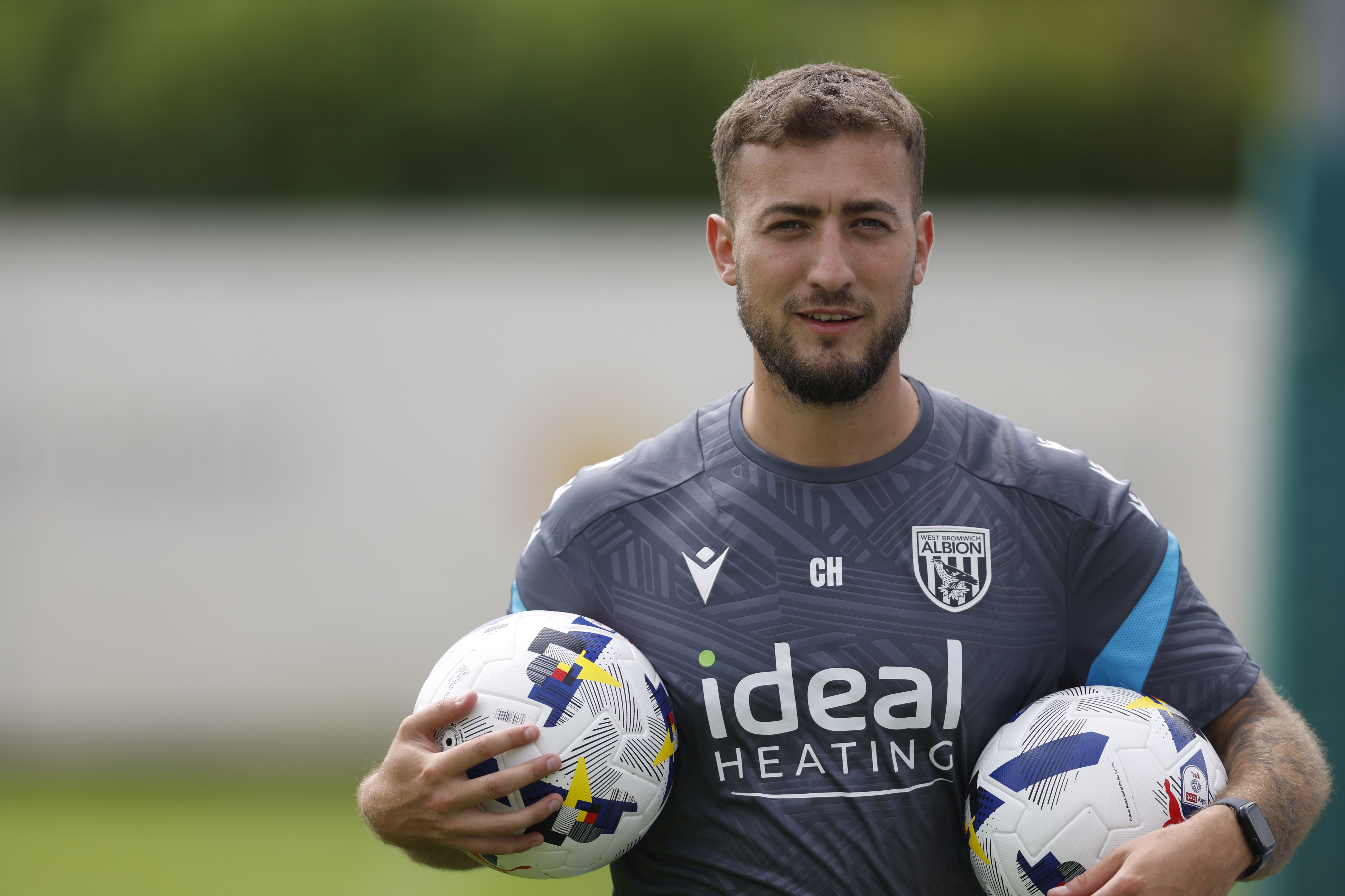 Albion kit man Curtis Holmes carrying two balls on the training pitch