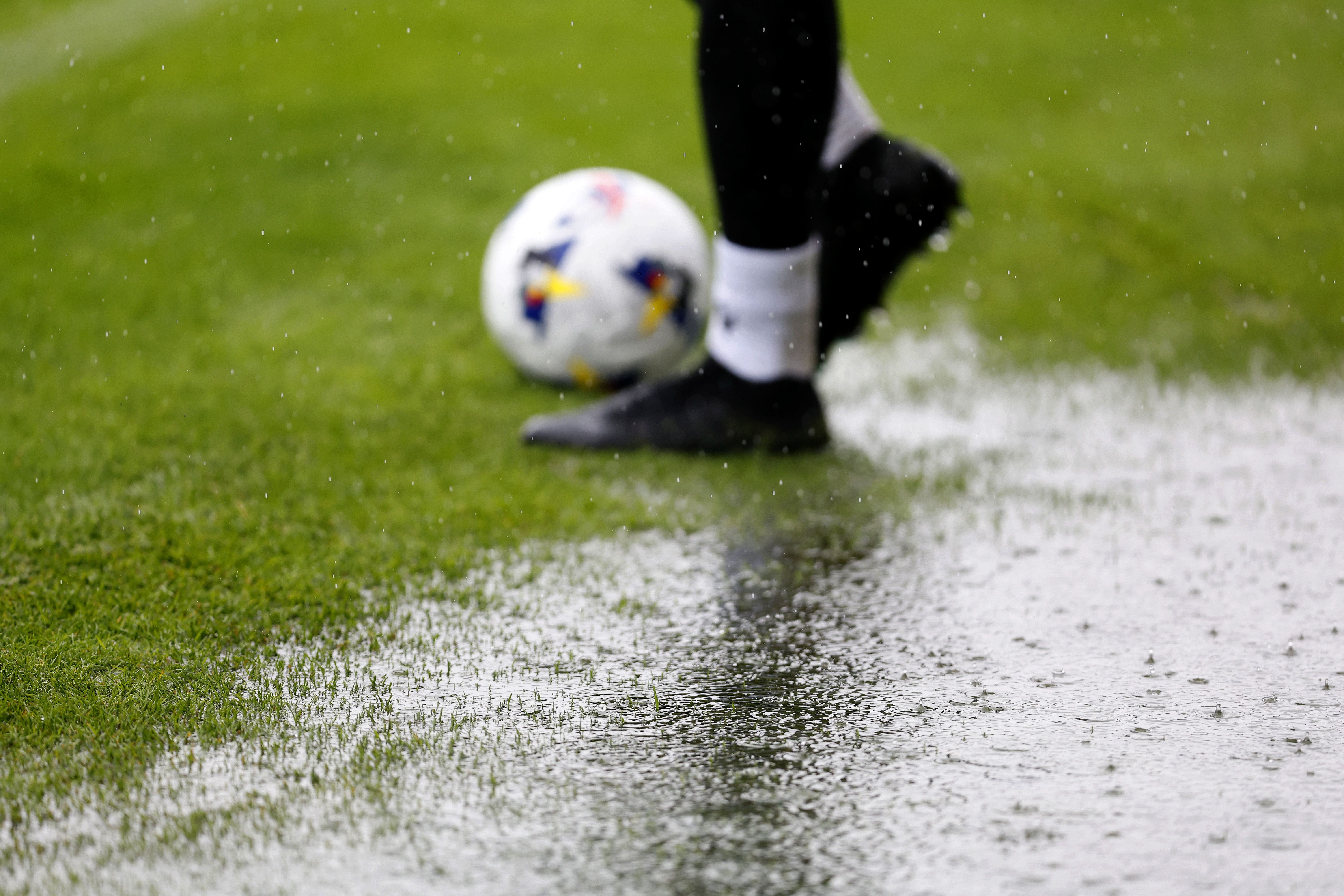 A general view of a rain puddle on the side of the pitch with a ball