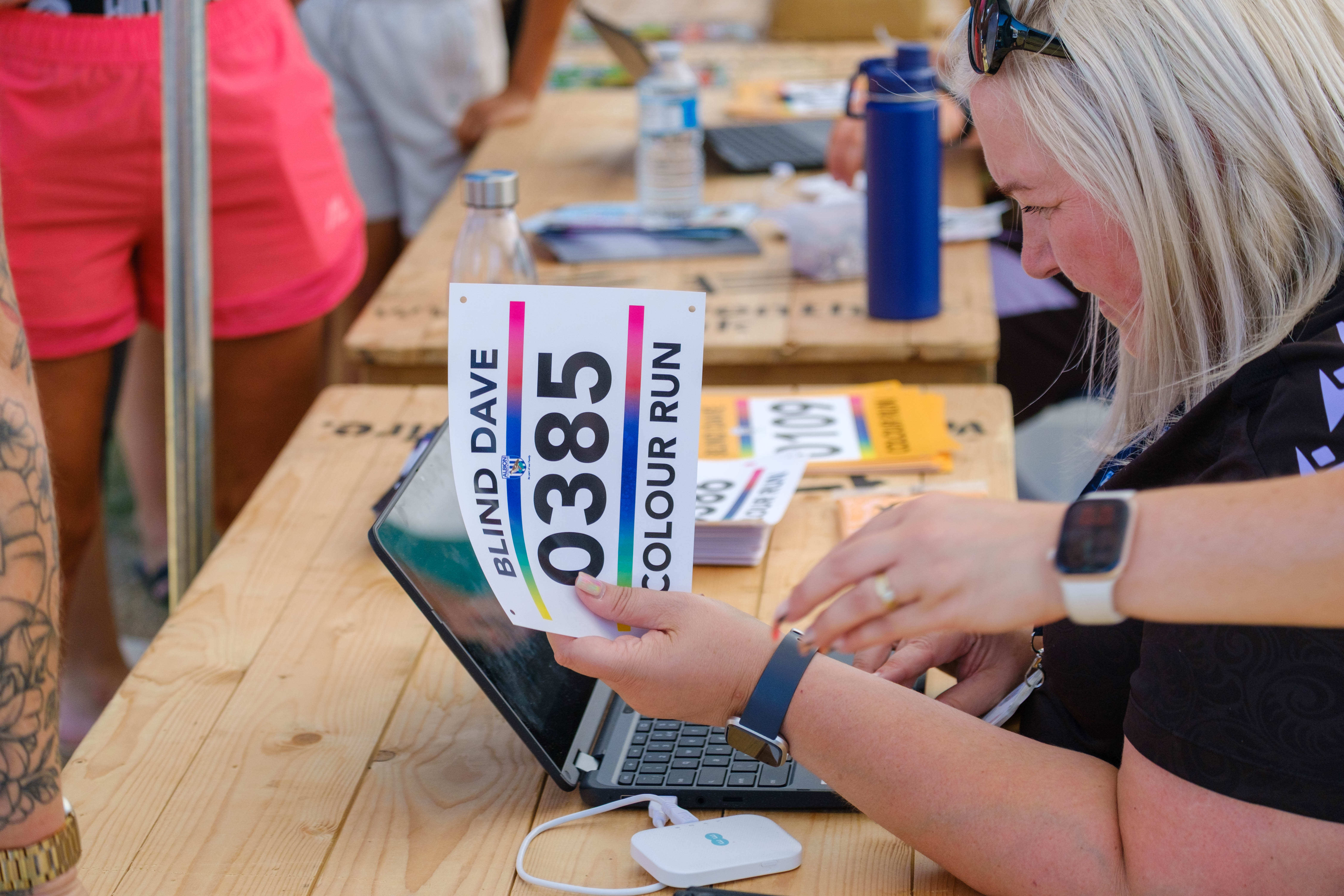 Foundation staff member handing on runners number at registration desk