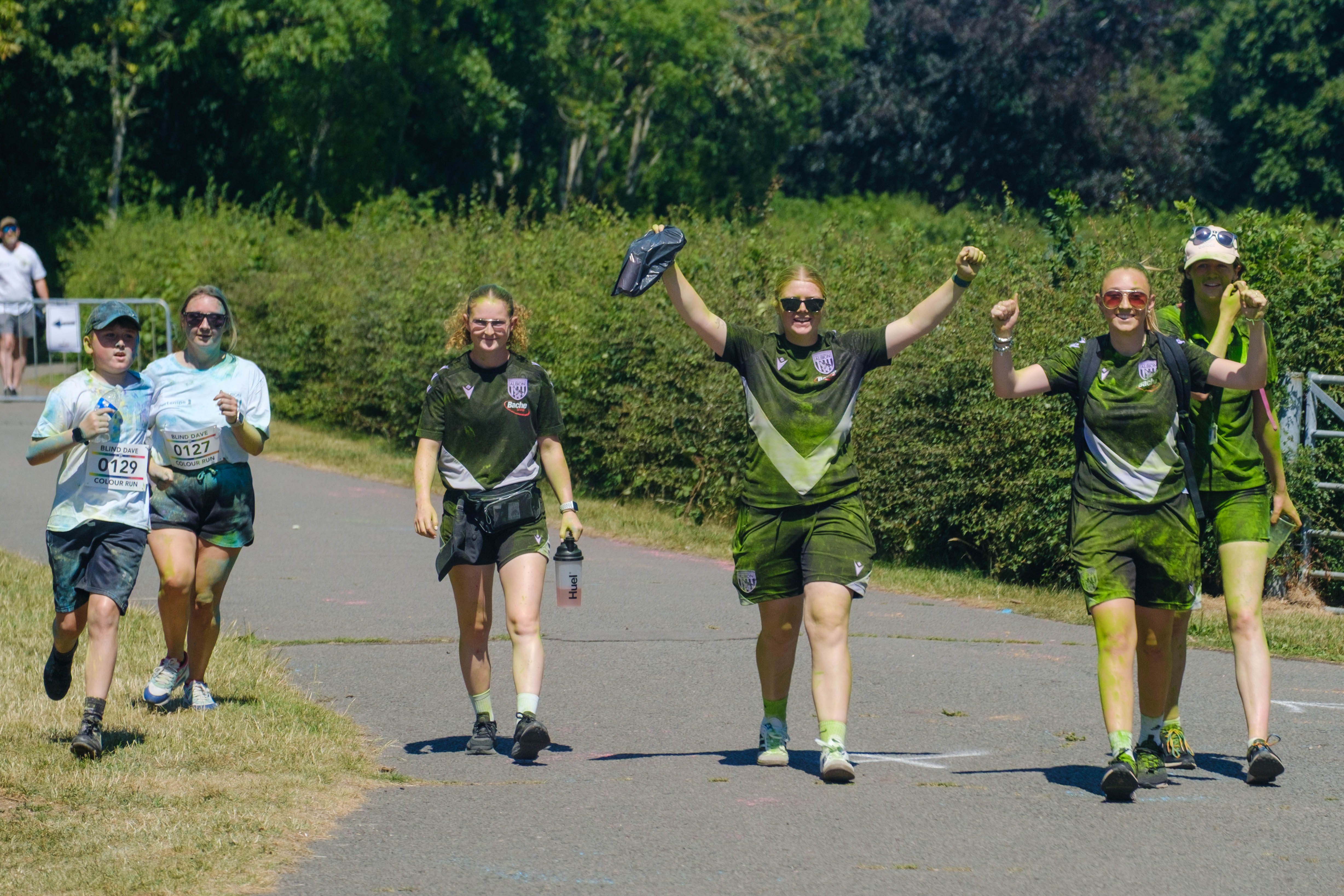 Four Foundation staff walking towards the finish line, with two have their arms raised. 