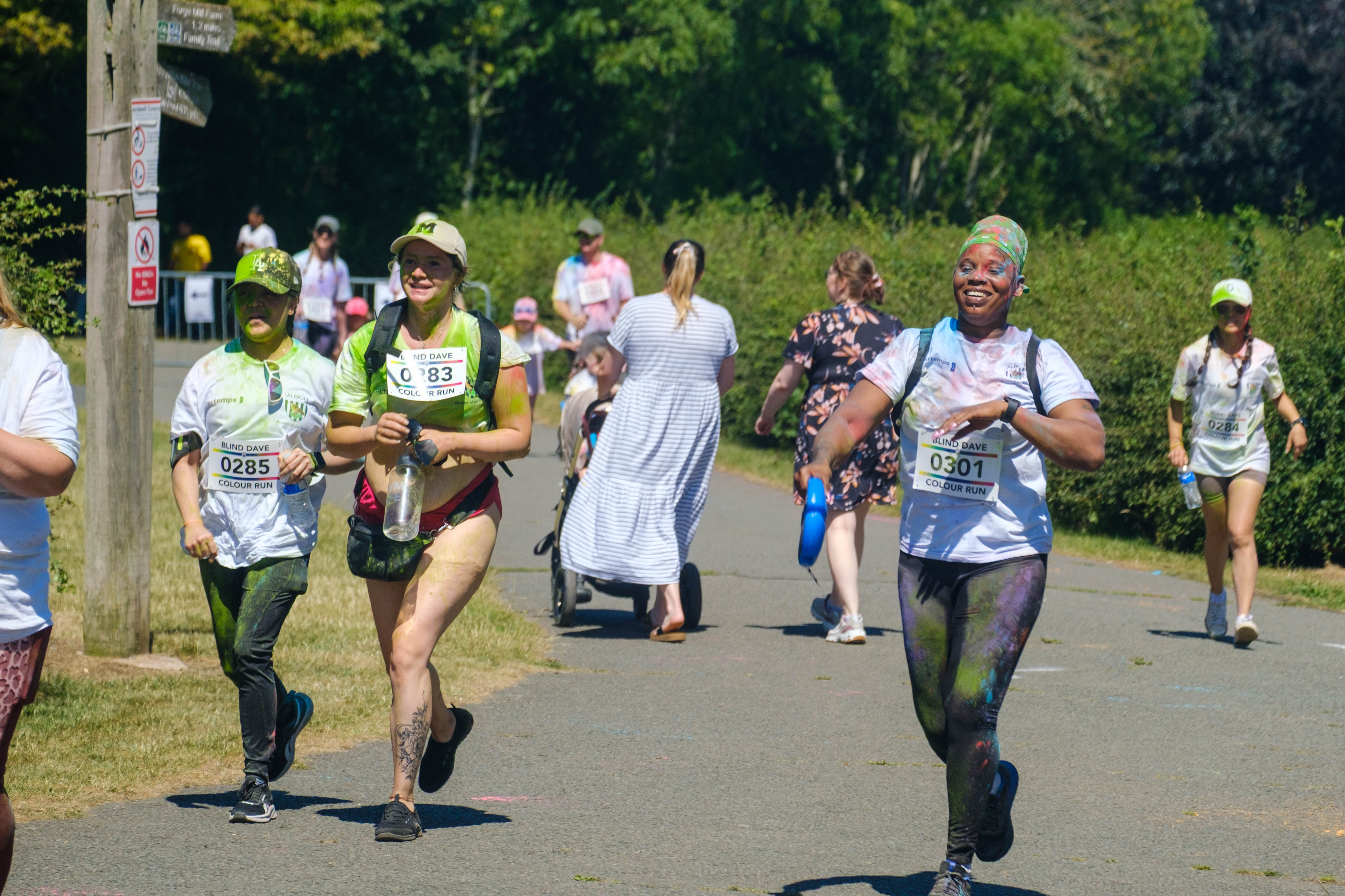 More runners smiling, heading towards the finish line.