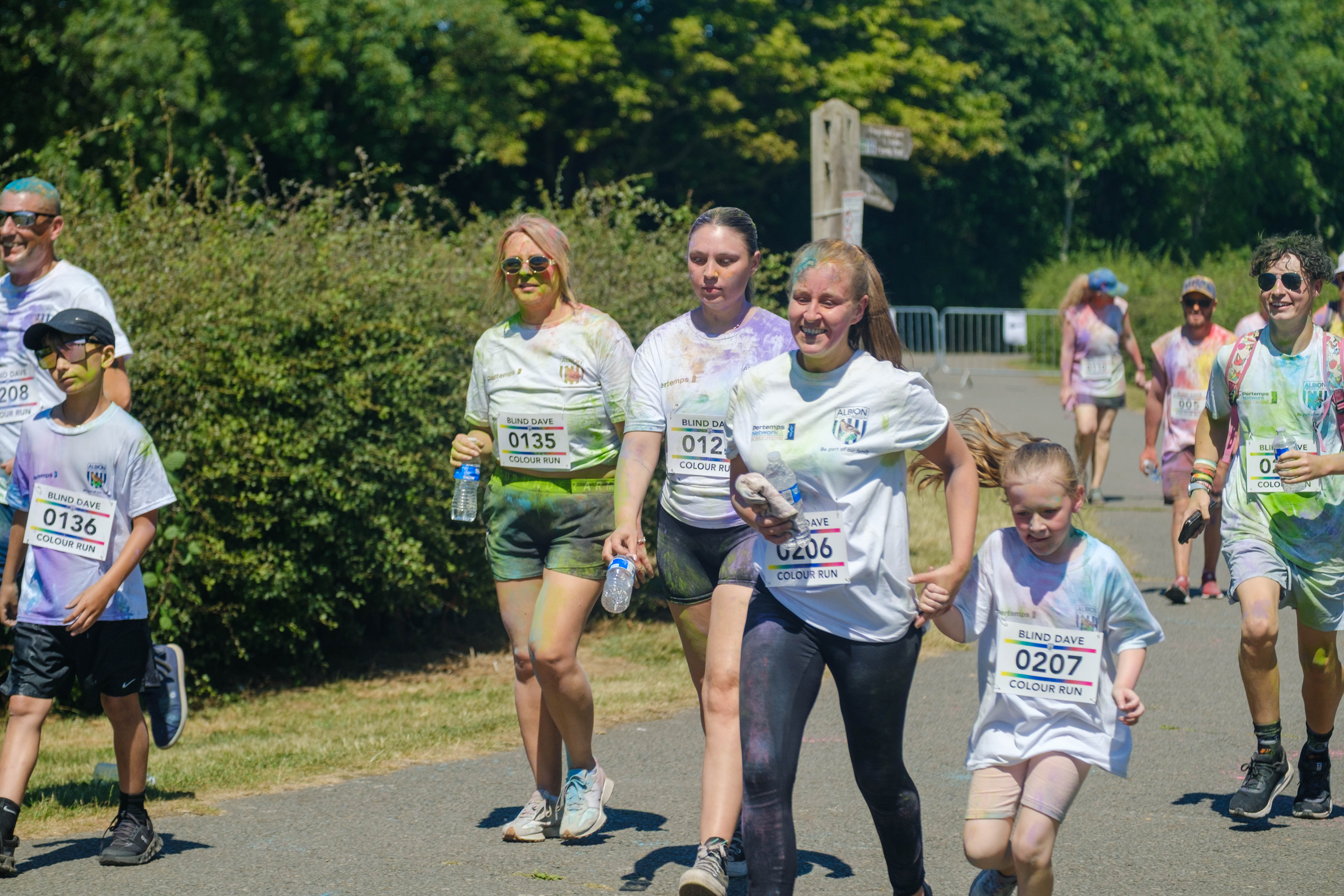 More runners smiling, heading towards the finish line.
