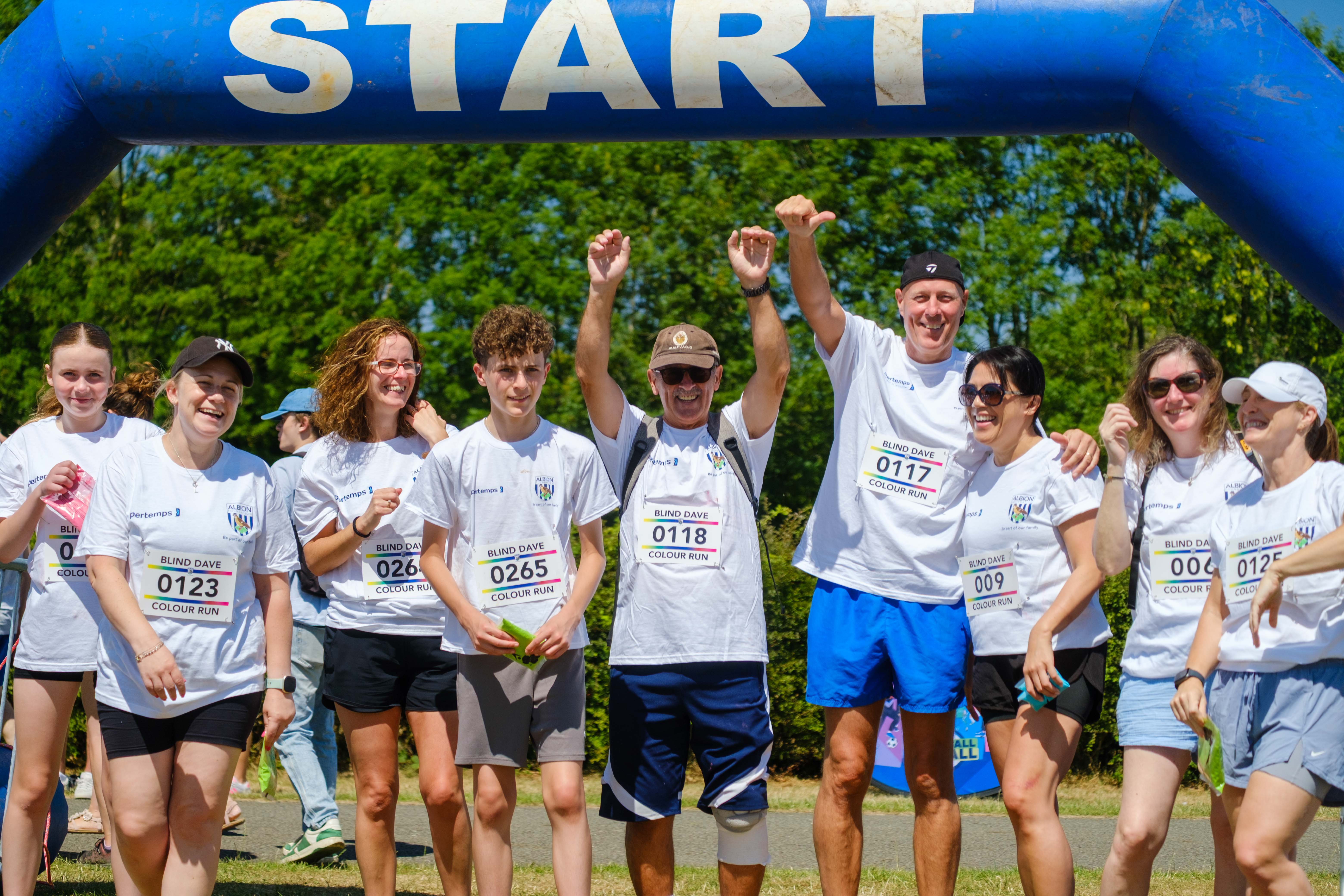 Group of participants under the starting arch, with a couple raising  their arms.