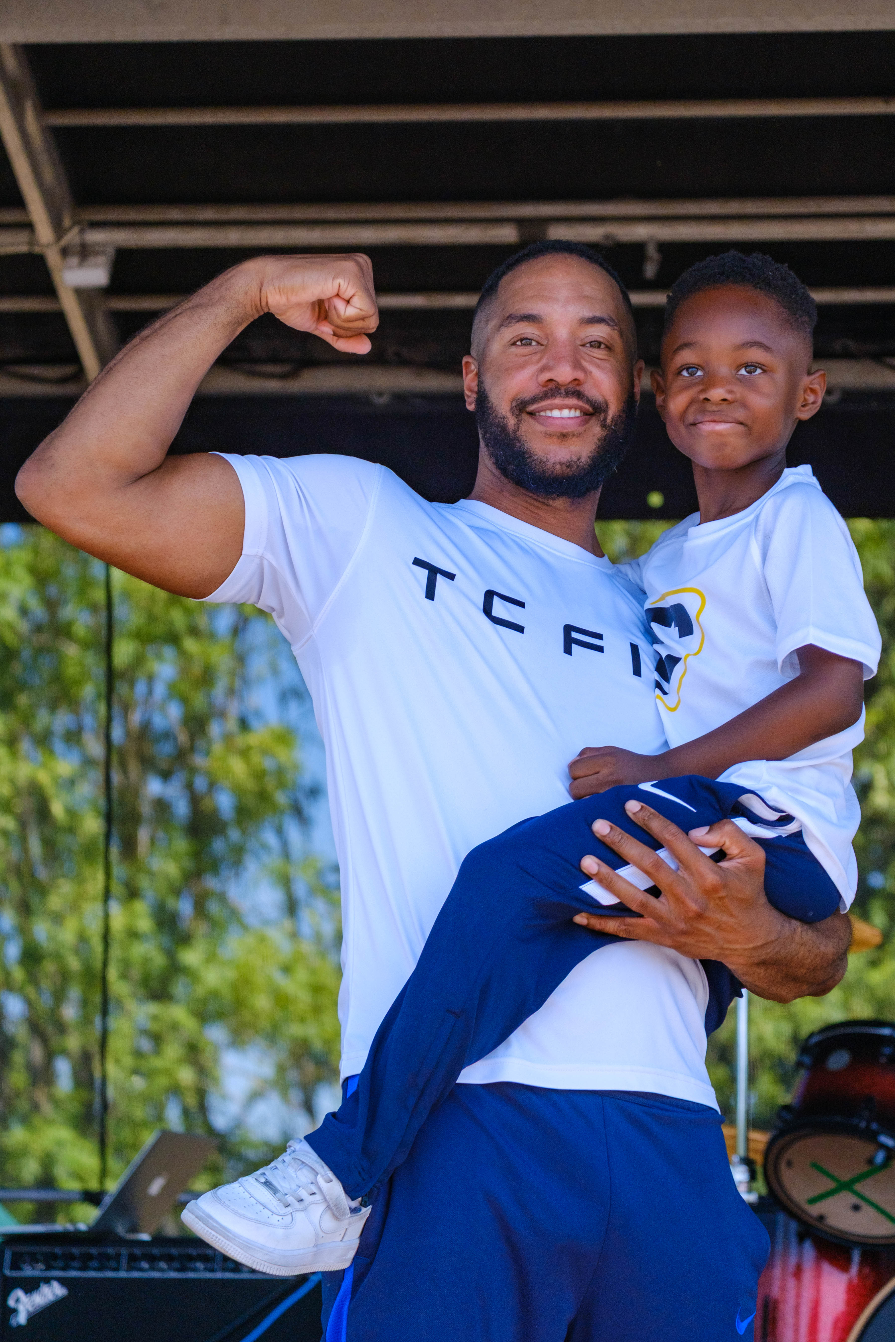 TC Fit Tony holding this son and flexing.