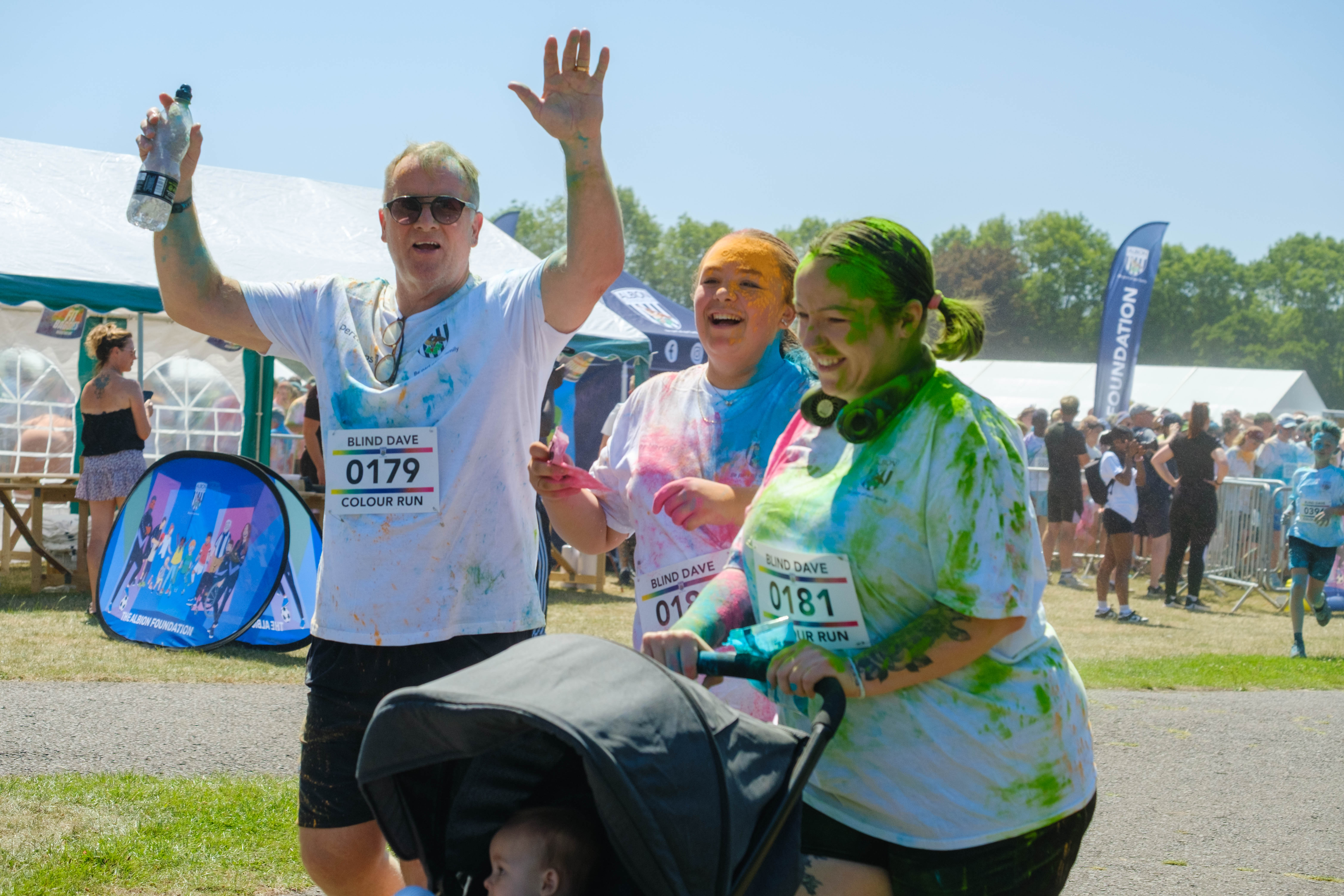 Three participants, one with a child in a push chair covered in paint. 