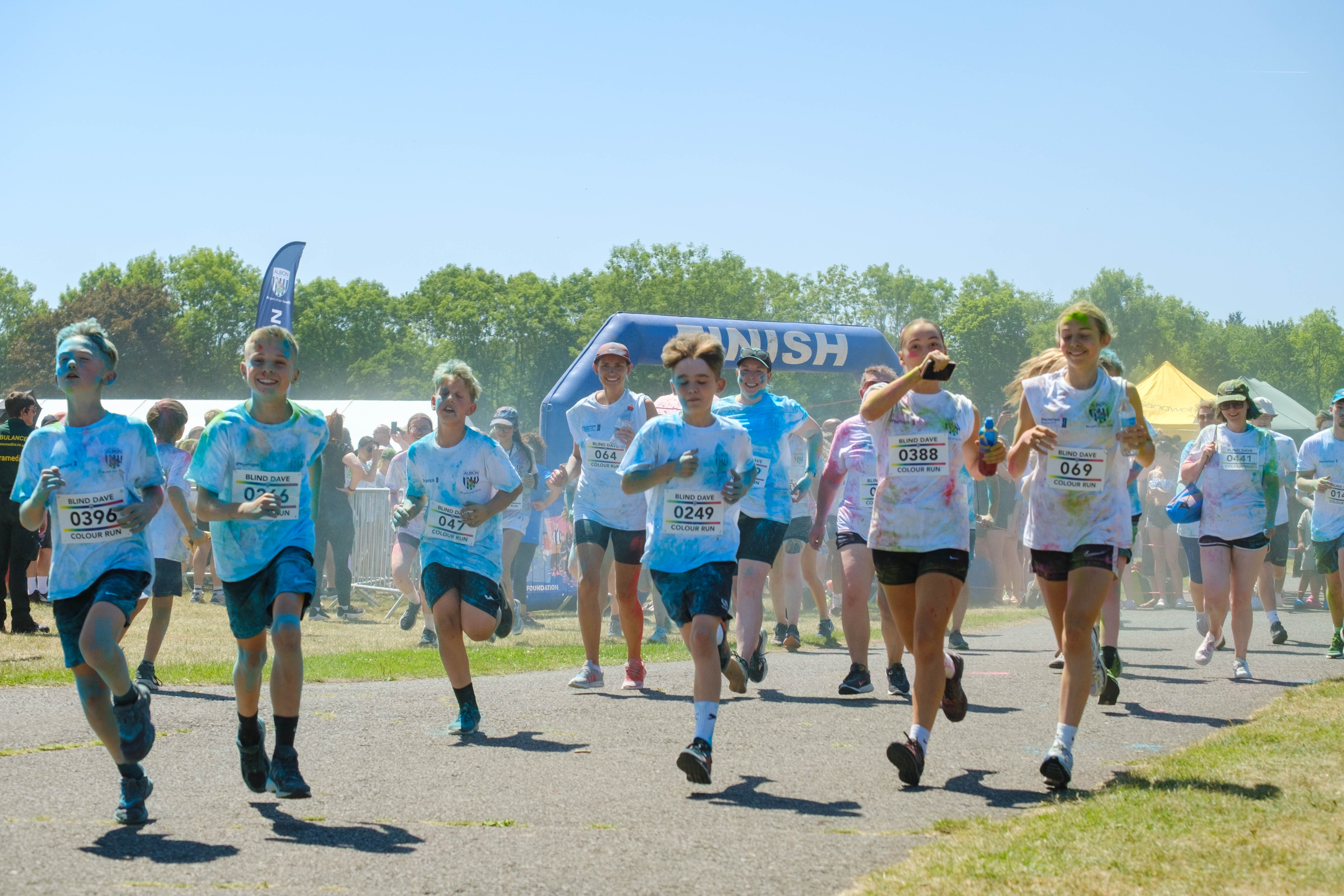 Large group of second wave runners, covered in paint, leaving the start line.