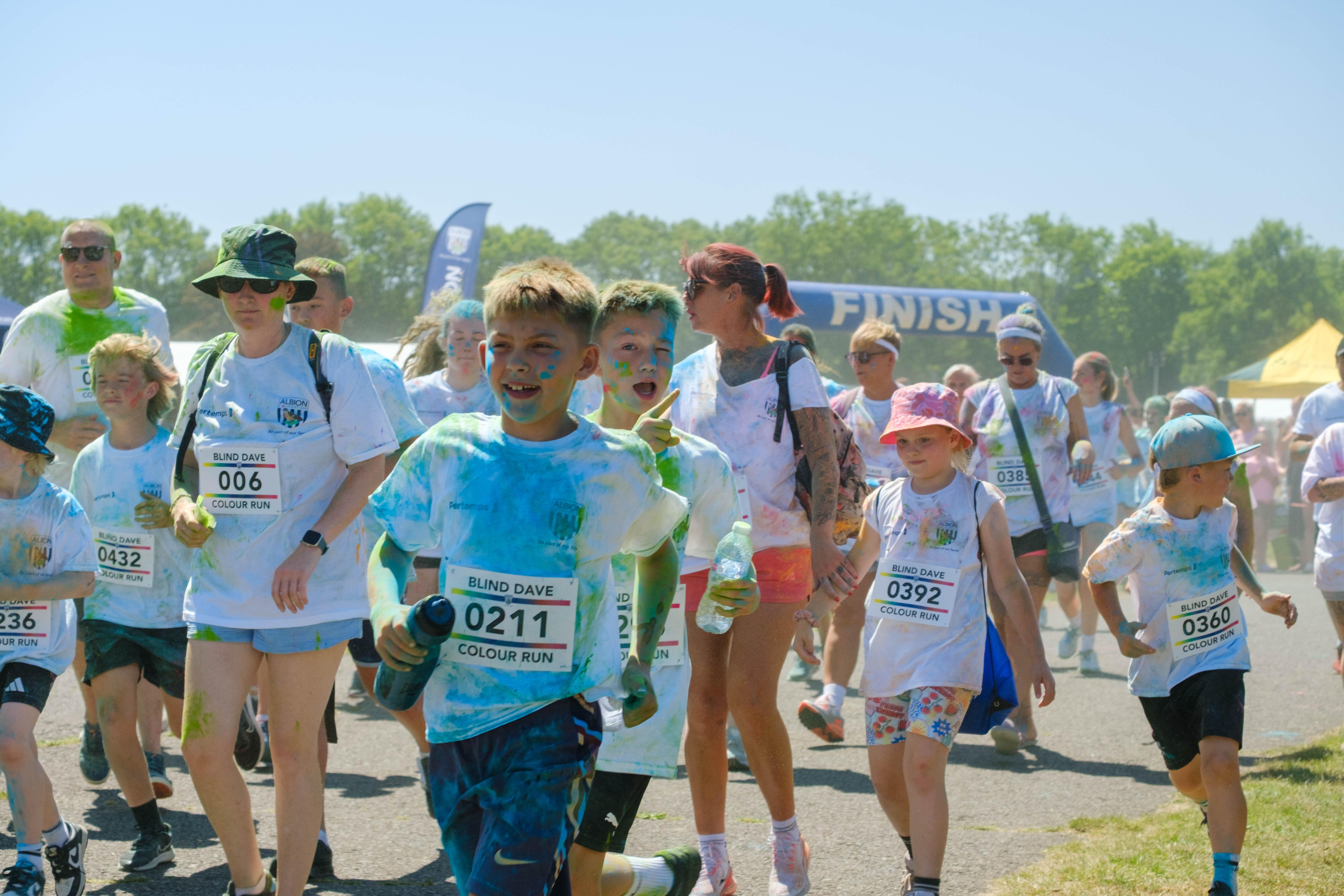 Large group of second wave runners, covered in paint, leaving the start line.