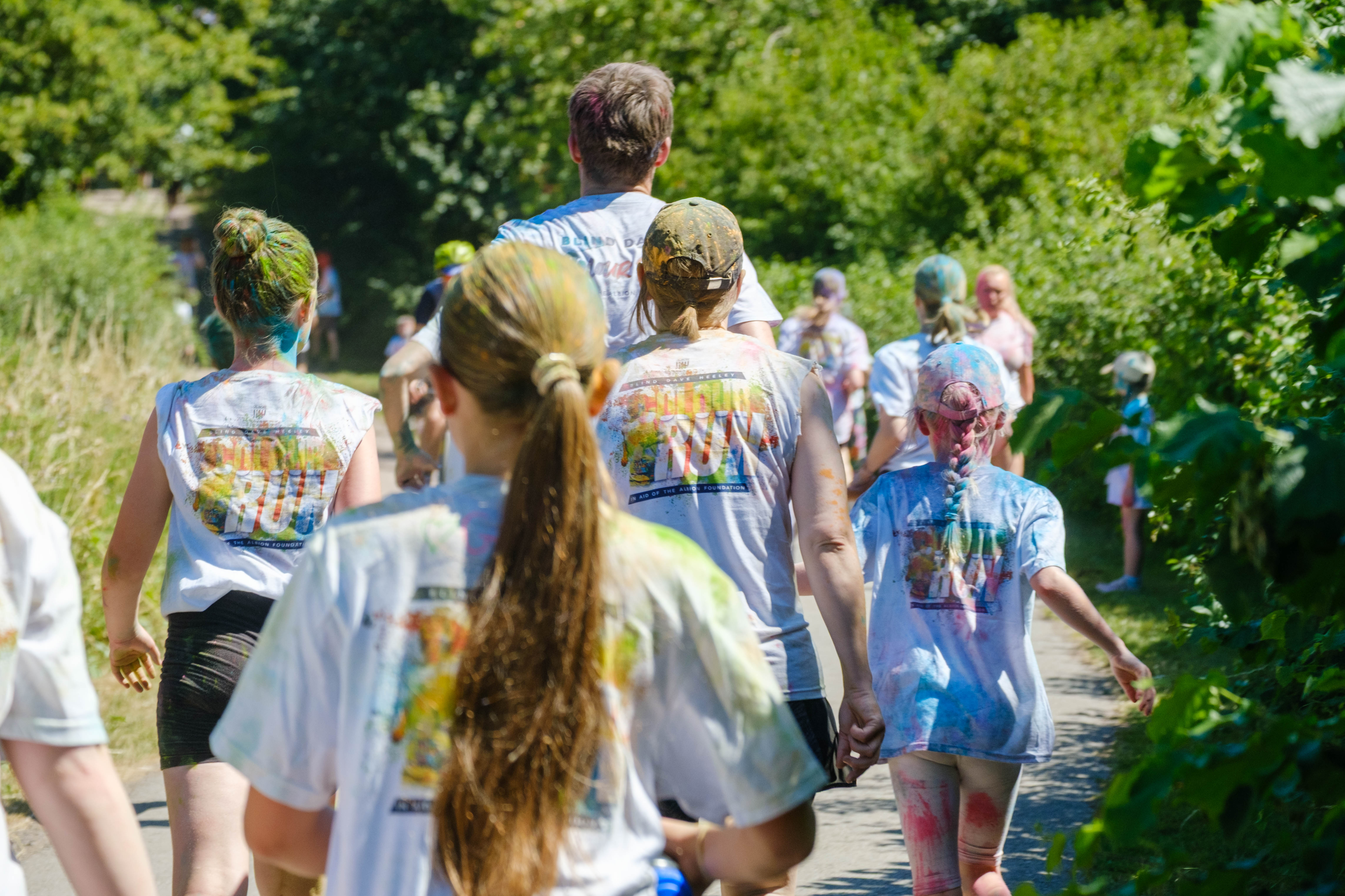 Backs of participants running through shaded greenery.