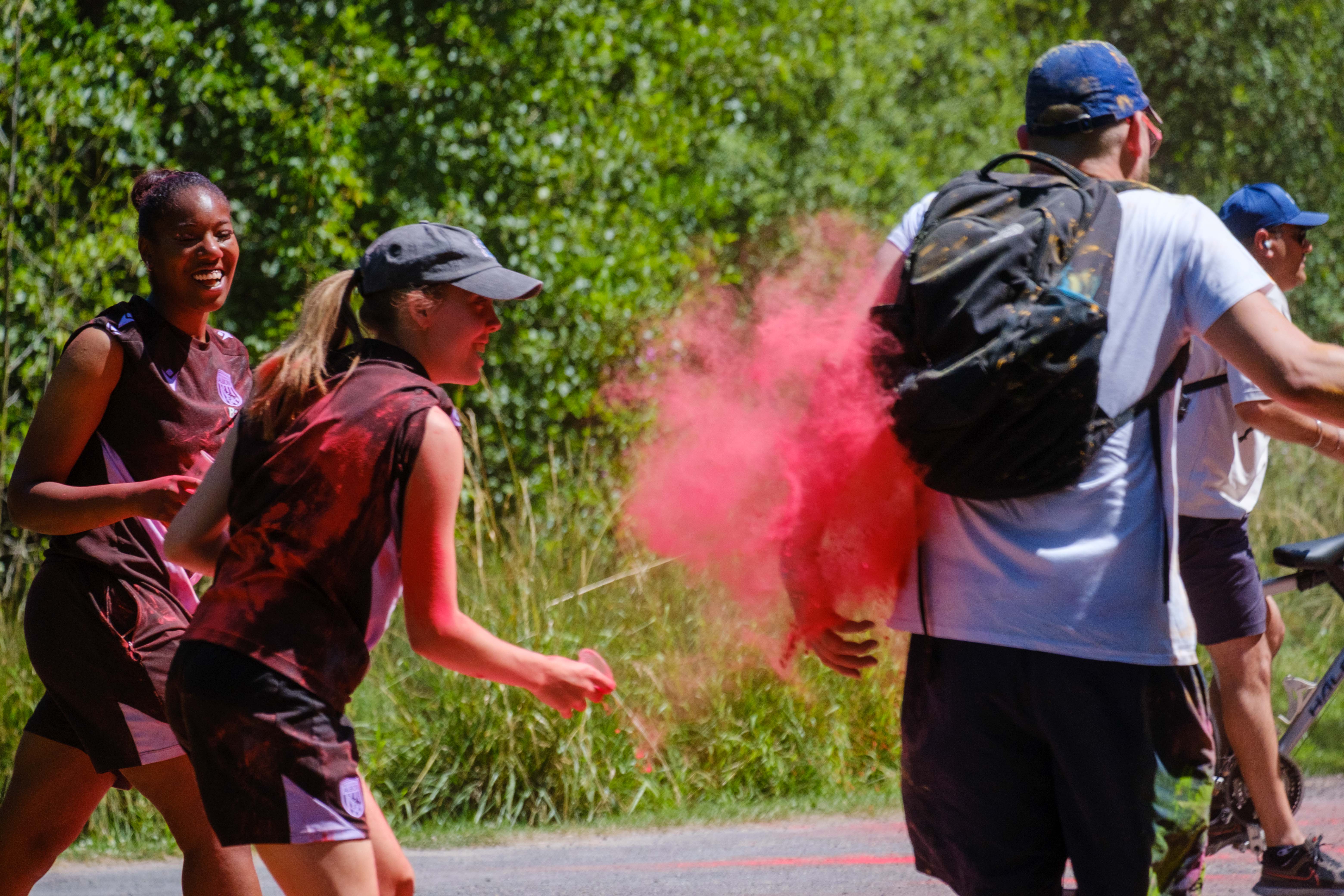 Two Foundation staff members aiming paint powder at a passing runner.