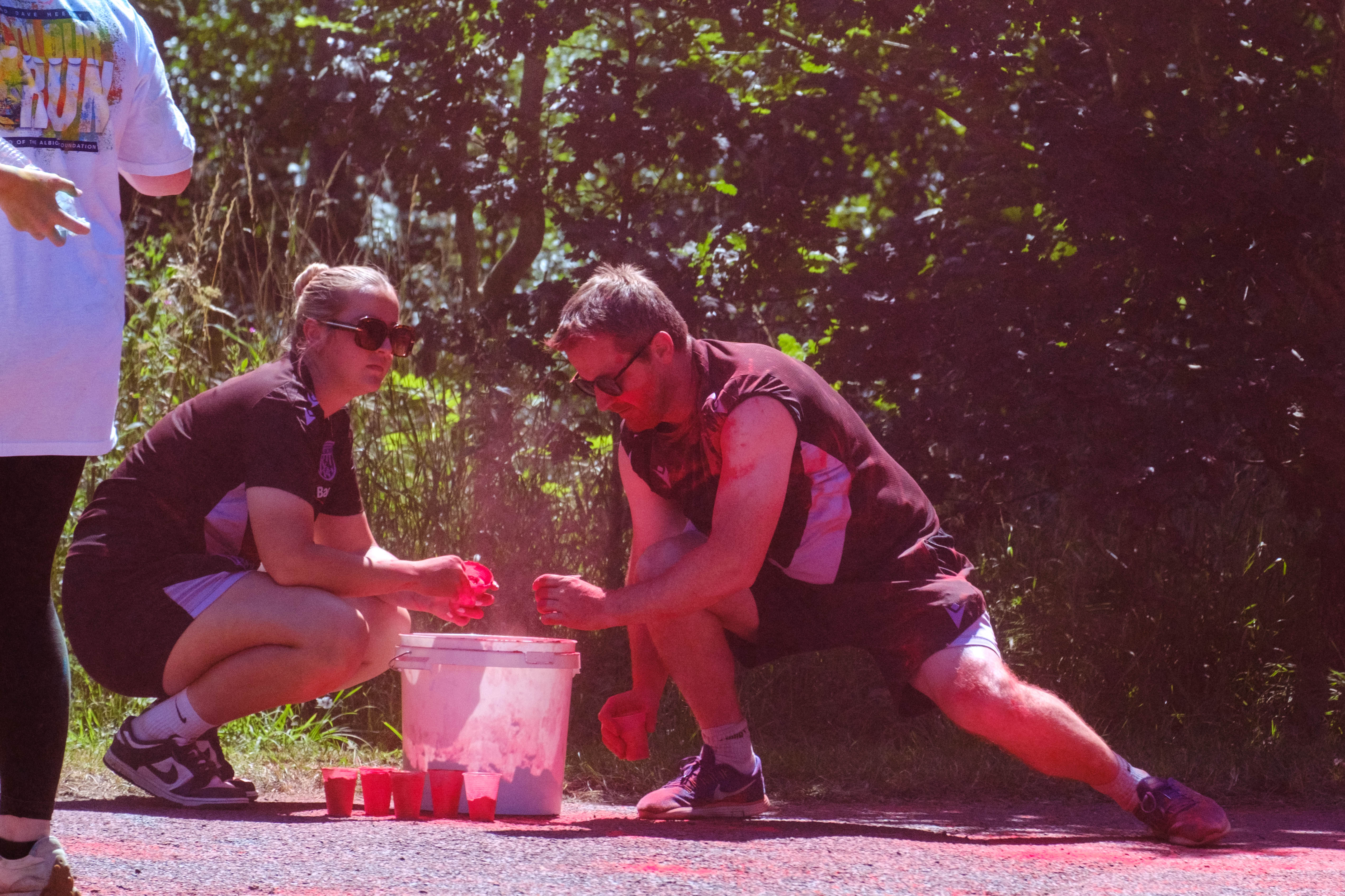 Close up of two Foundation staff members topping up their cups with paint powder.