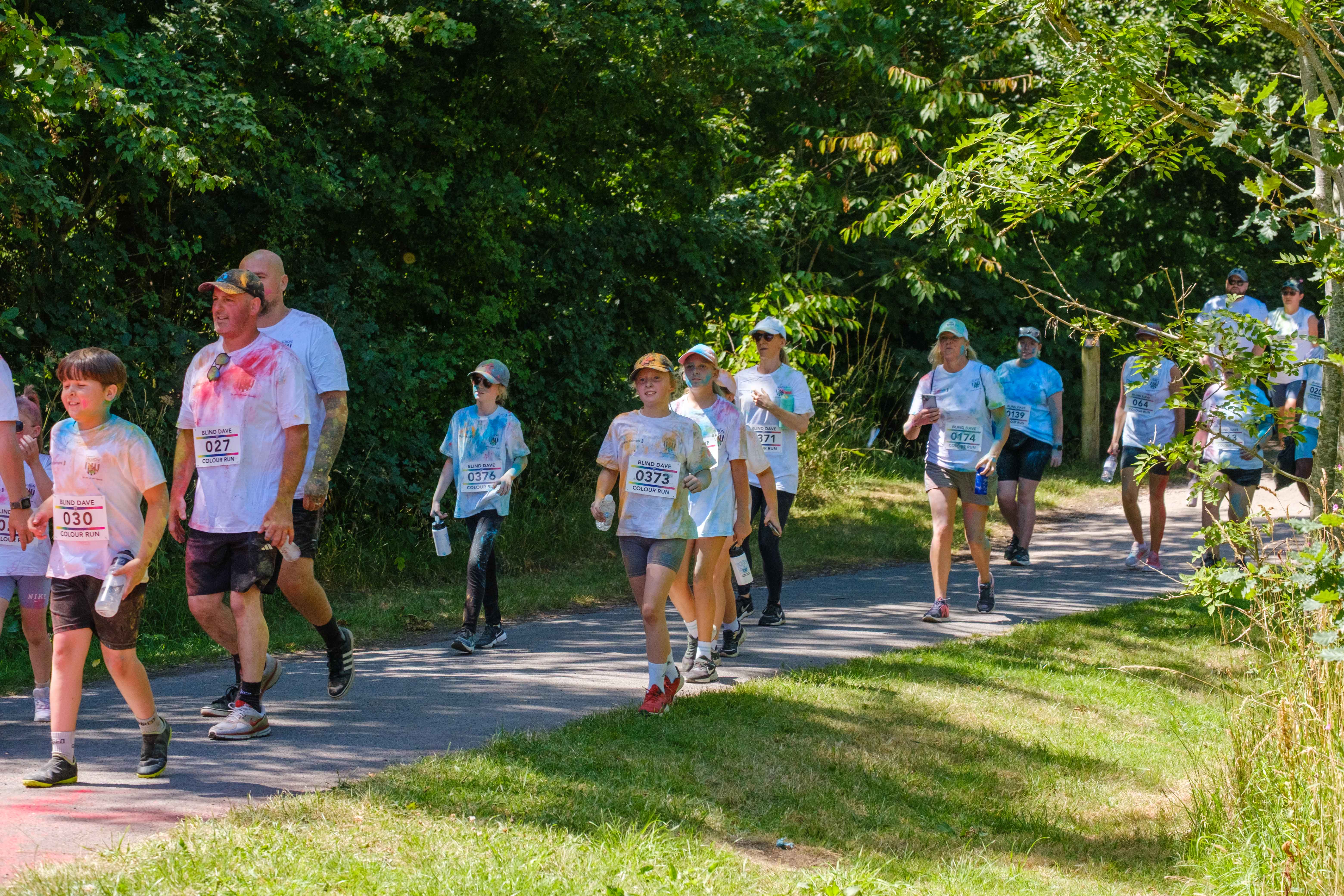 Participants running along shaded greenery.