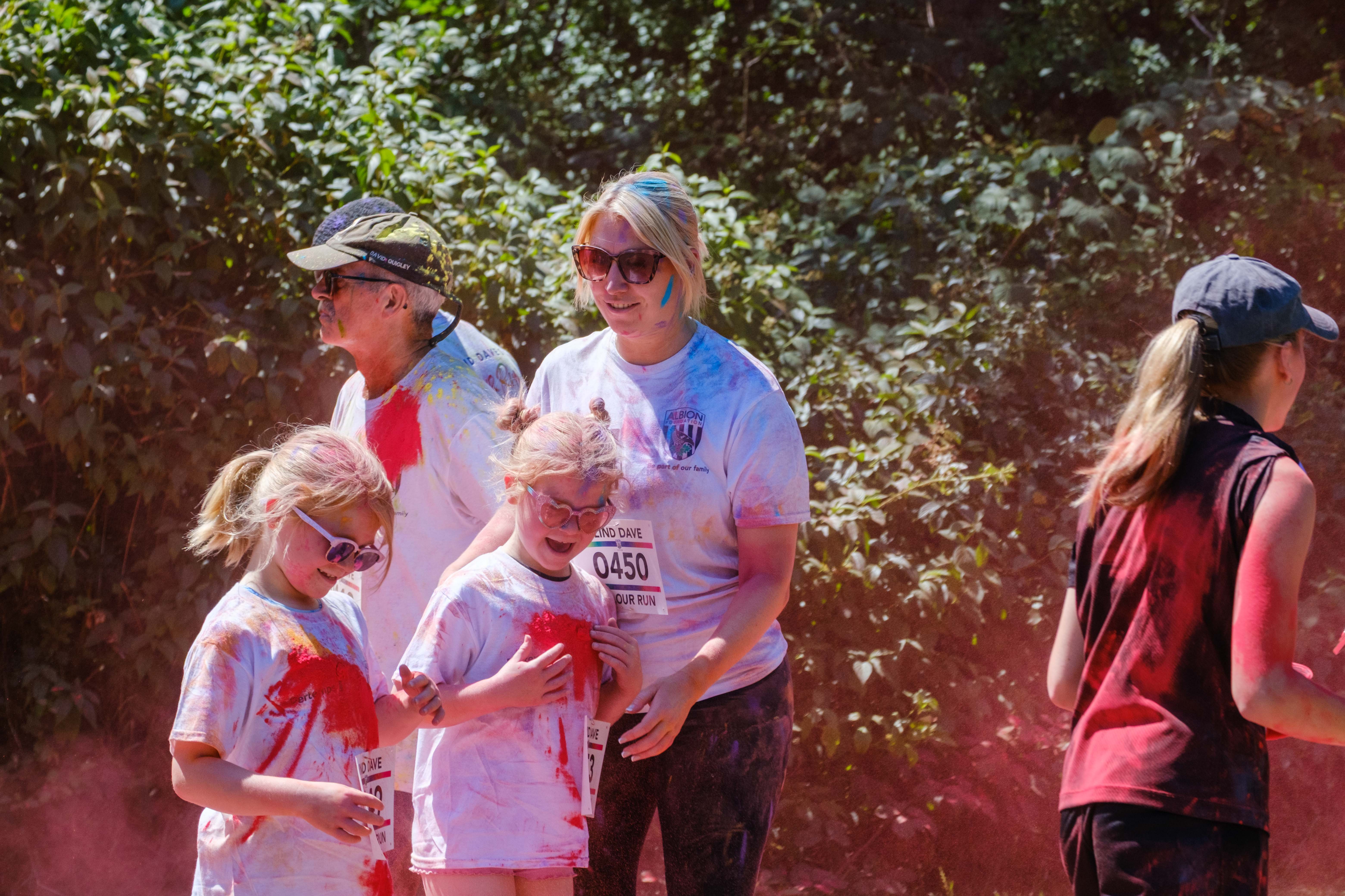 Runners passing colour station being douse with red powder.