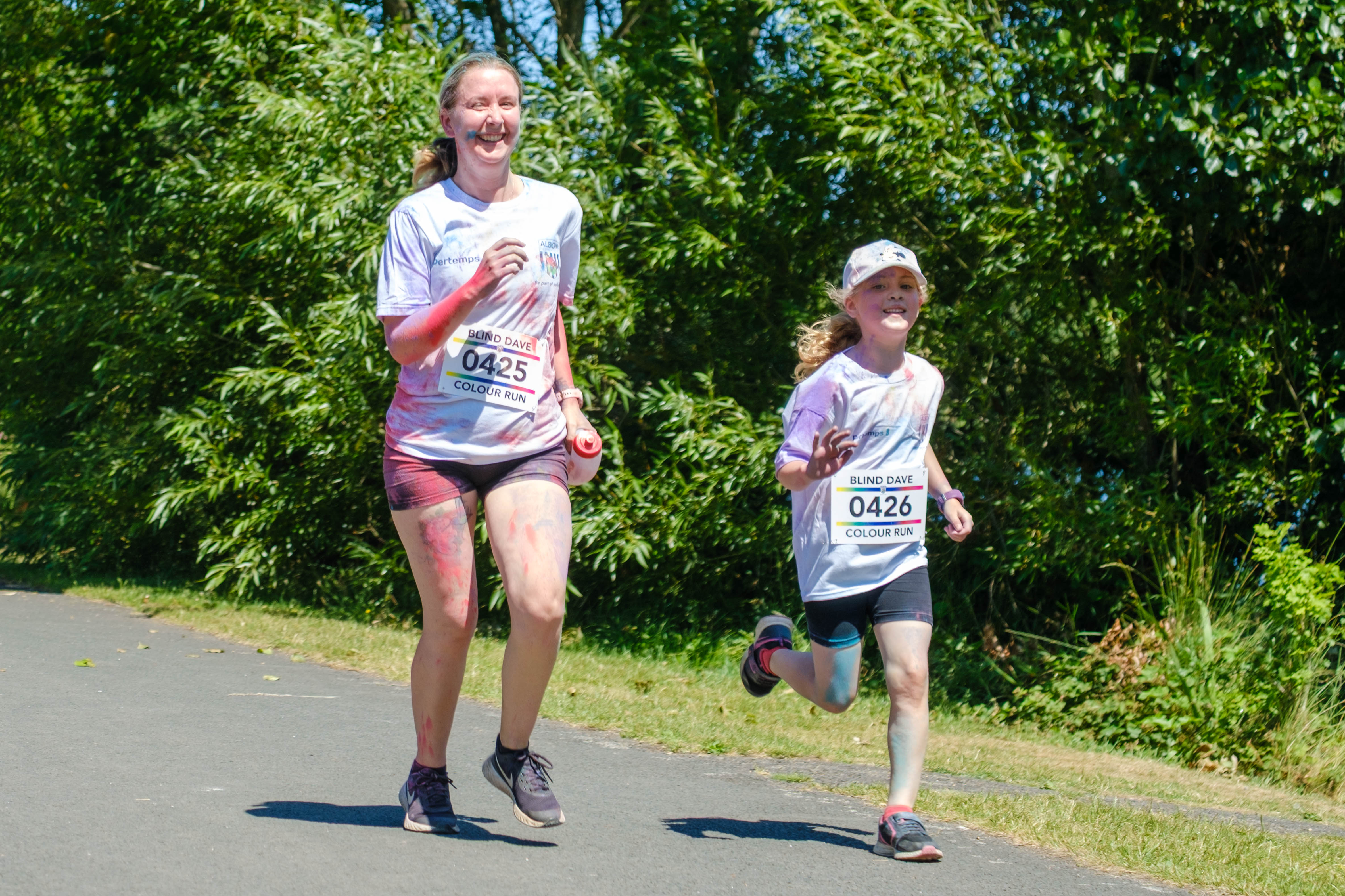 Mother and daughter, waving and smiling, running on the path.