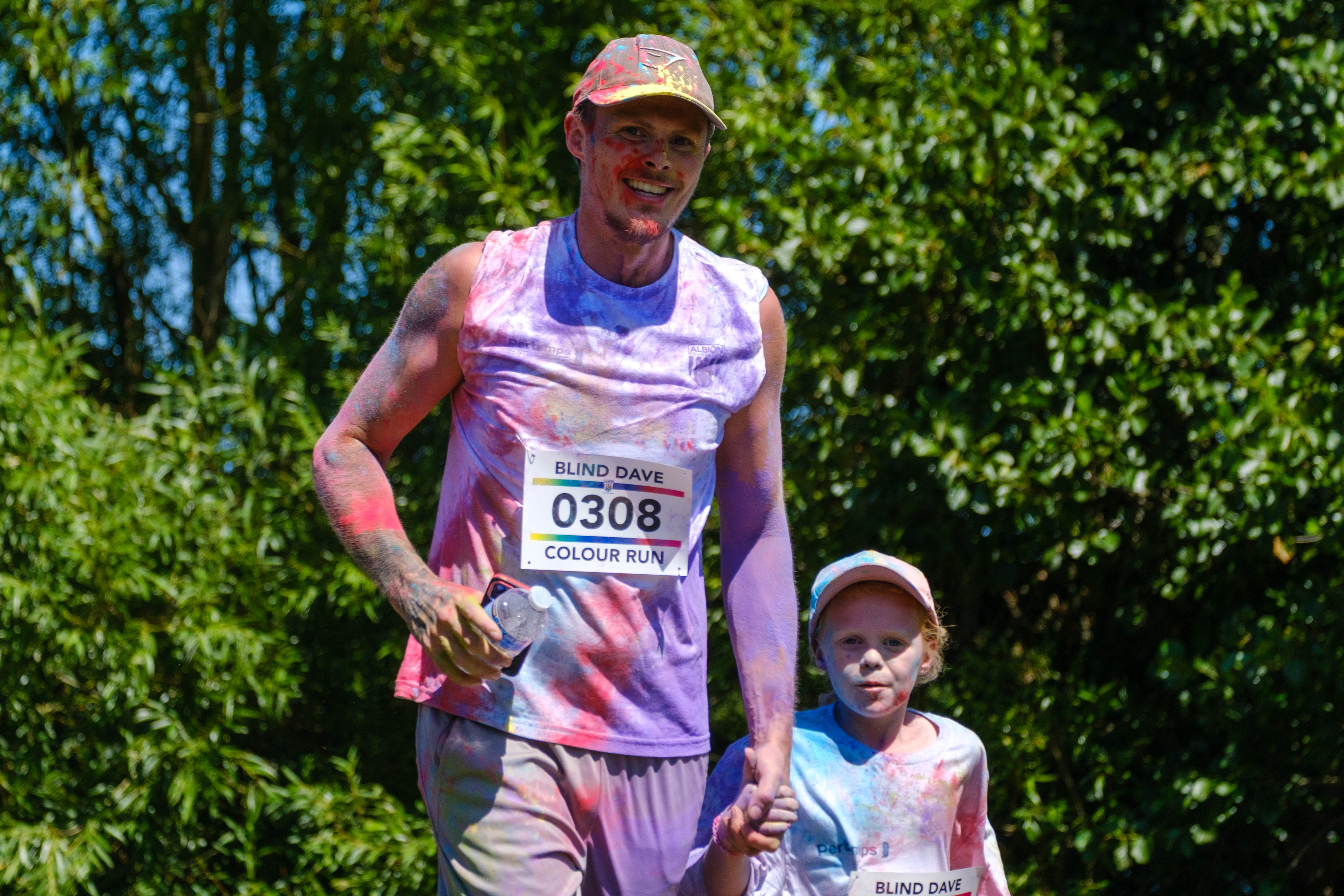 Father holding child hand, covered in multiple tones of paint