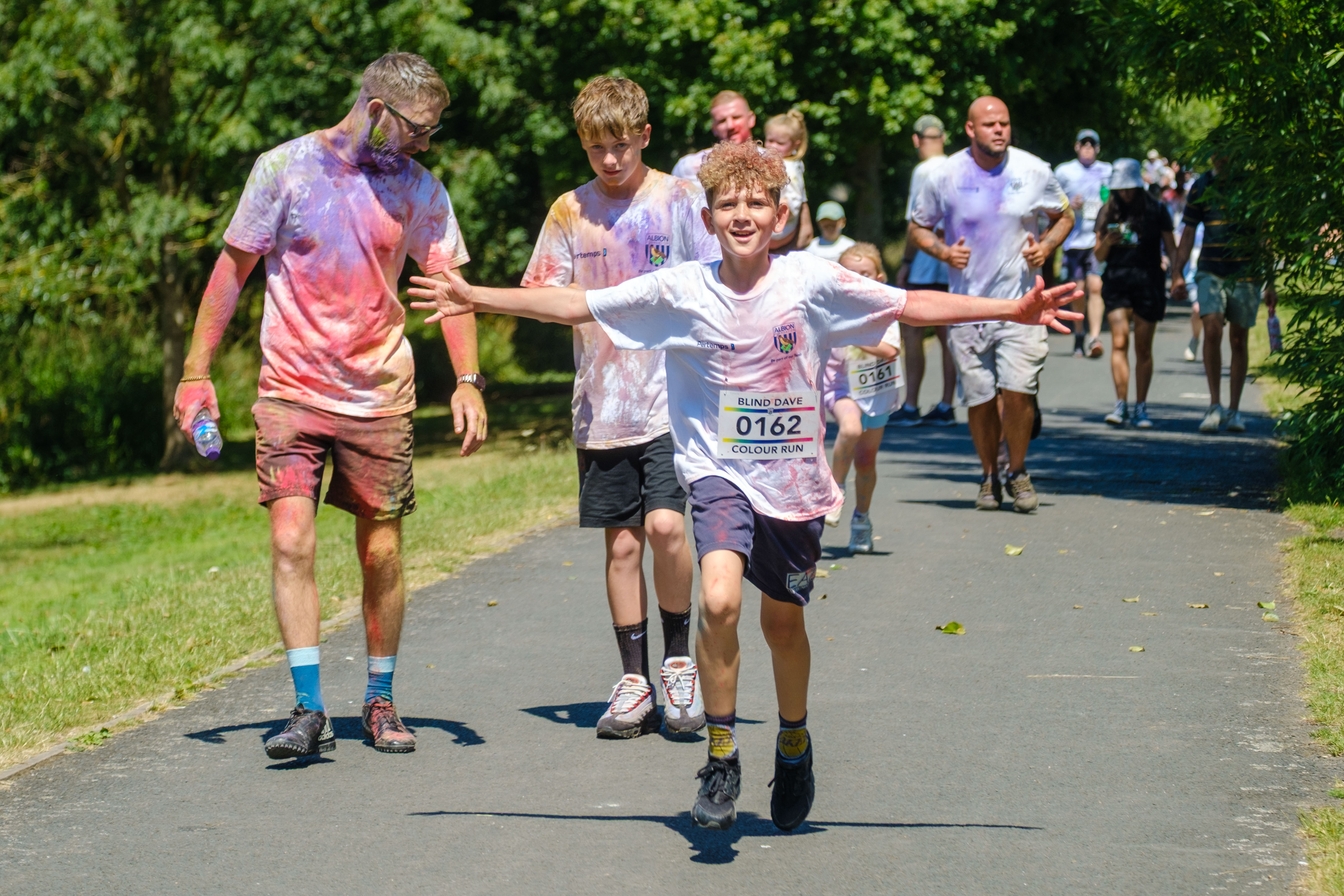 Young runner, with arms stretched out. Group of runners in the background.