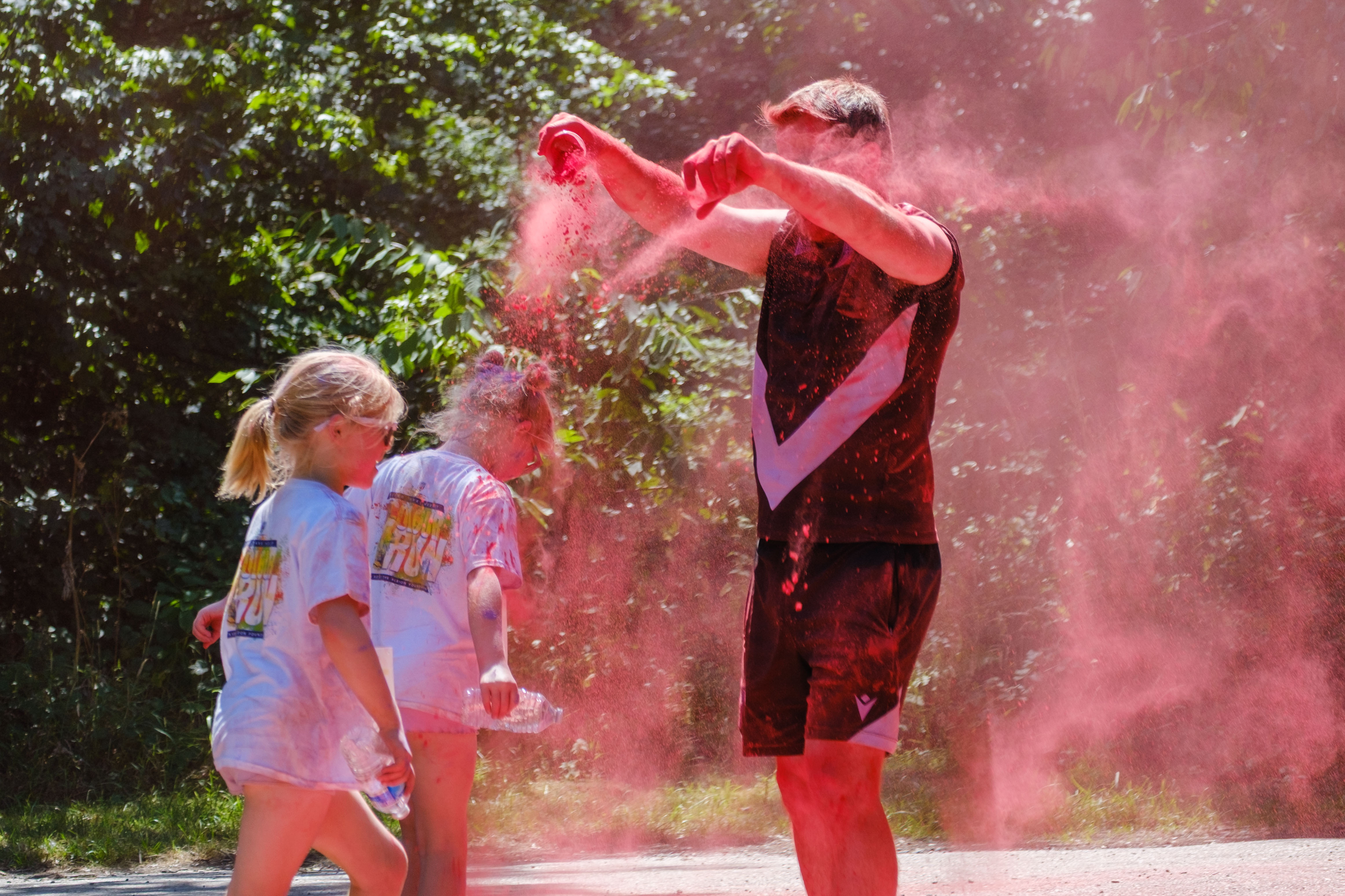 Foundation staff member dousing two young runners in red powder.