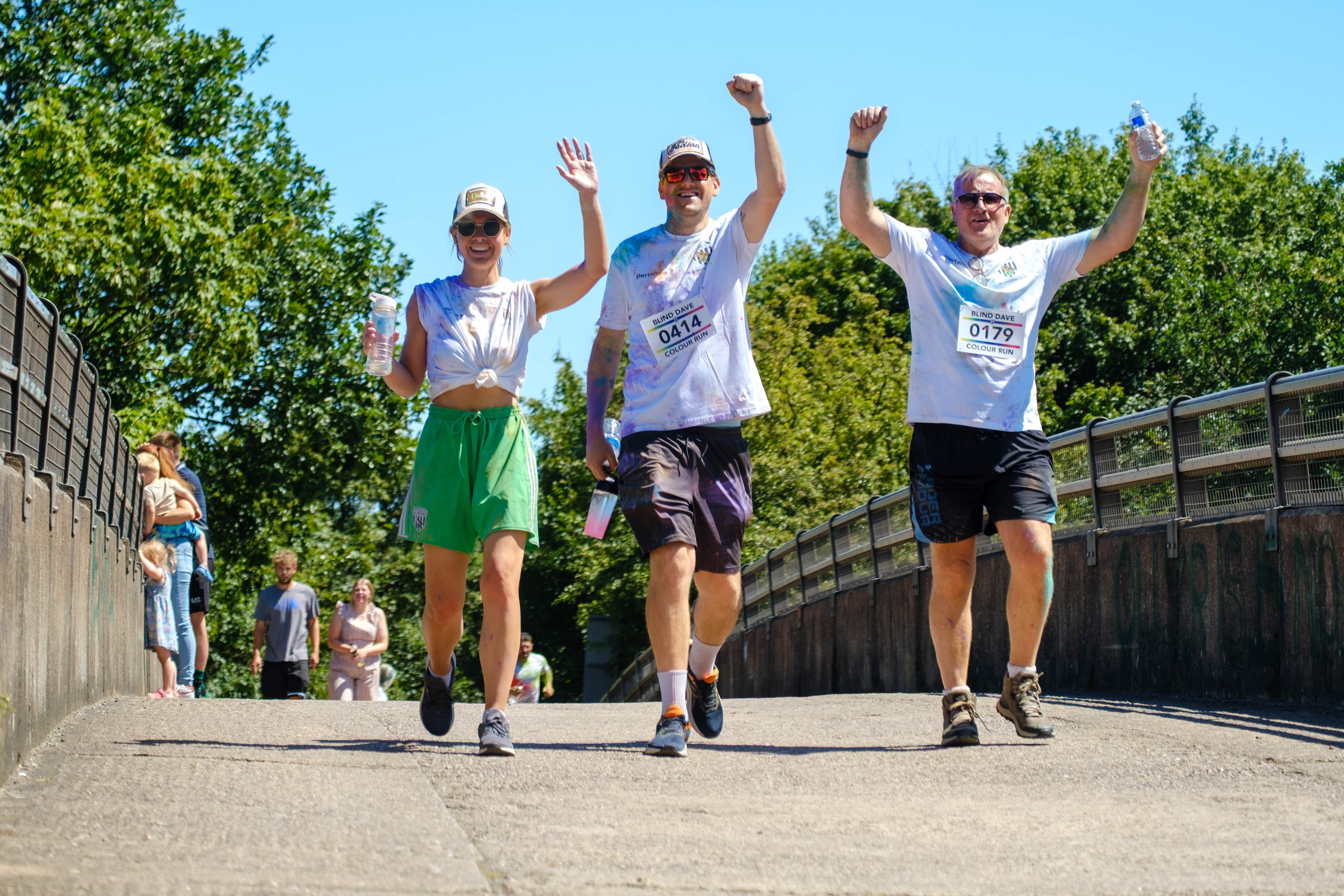 Three participants walking across the motorway bridge, with raised arms.