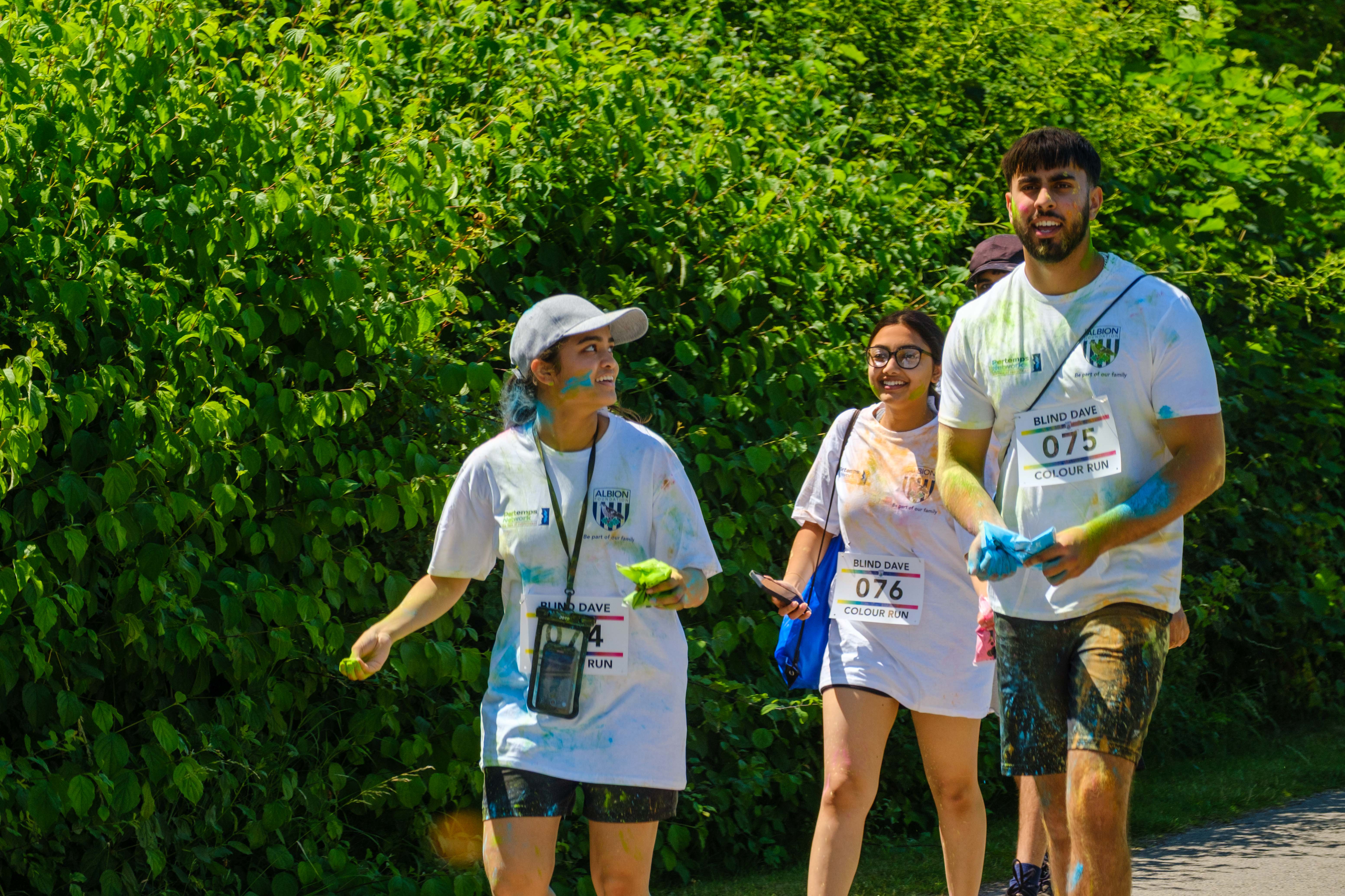 Four runners walking alongside the shrubs.