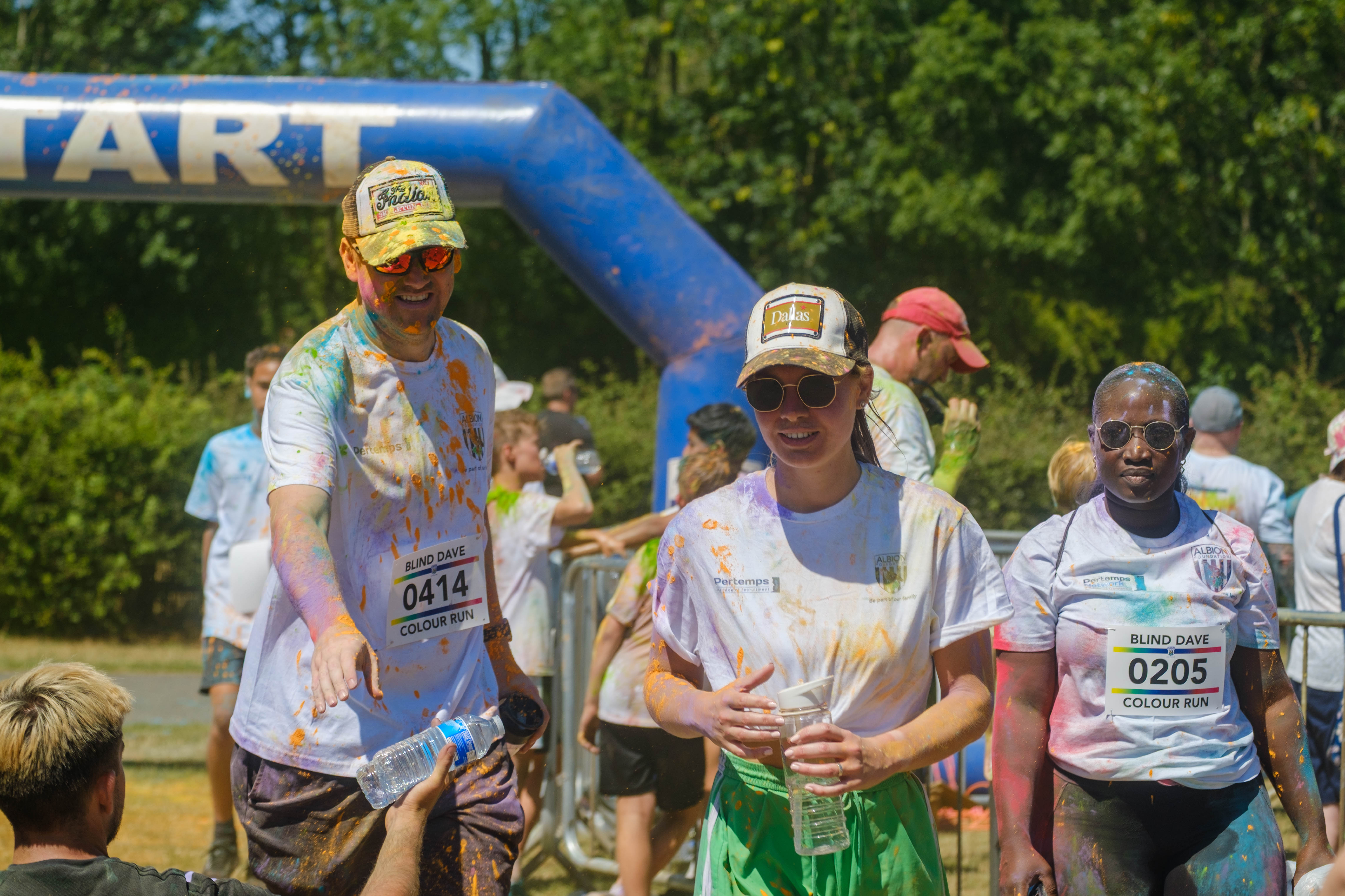 Two runners in trucker hats grabs bottles of water from Foundation staff at the end of the run.