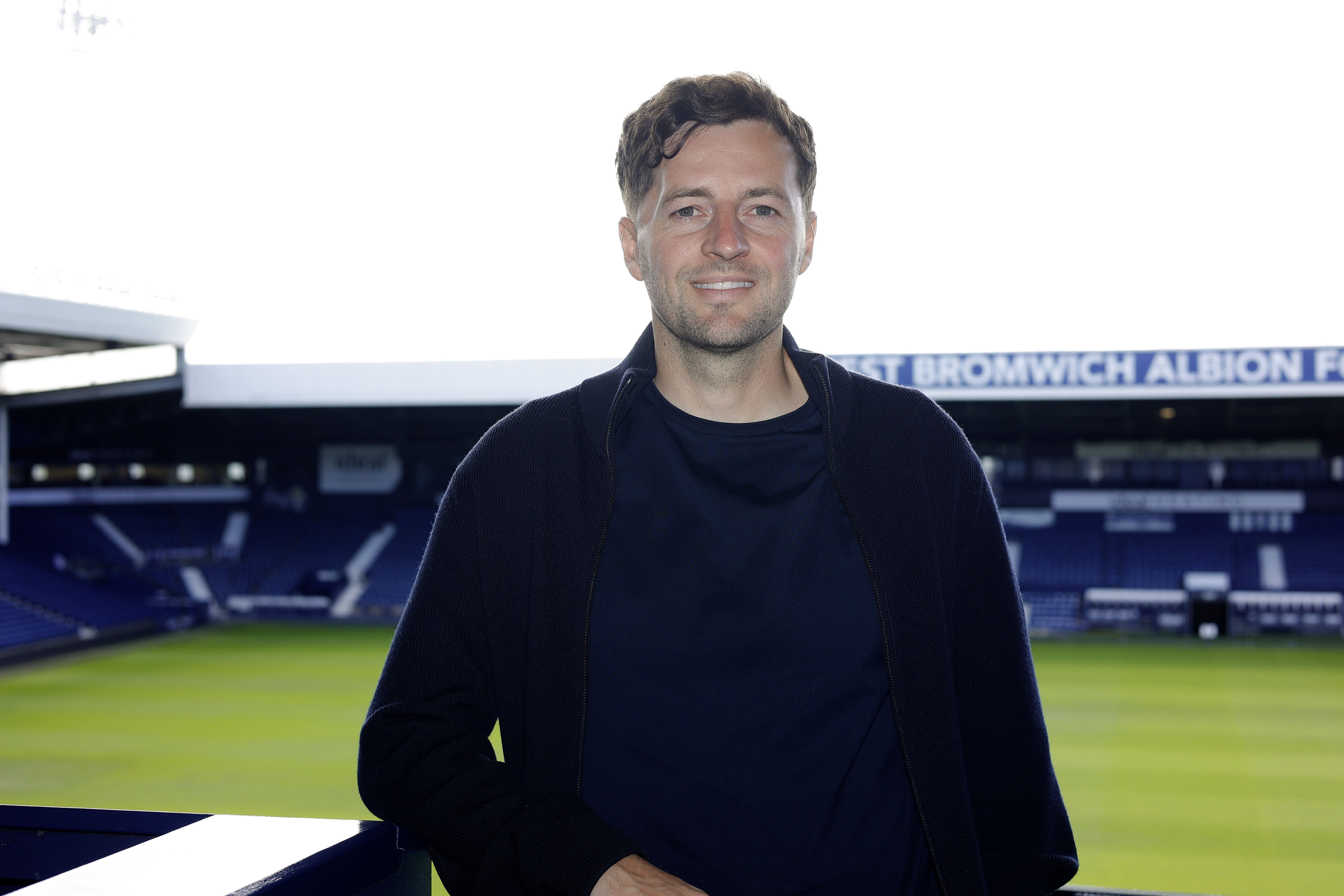 Ryan Mason posing for a photo at The Hawthorns with the West Stand behind him