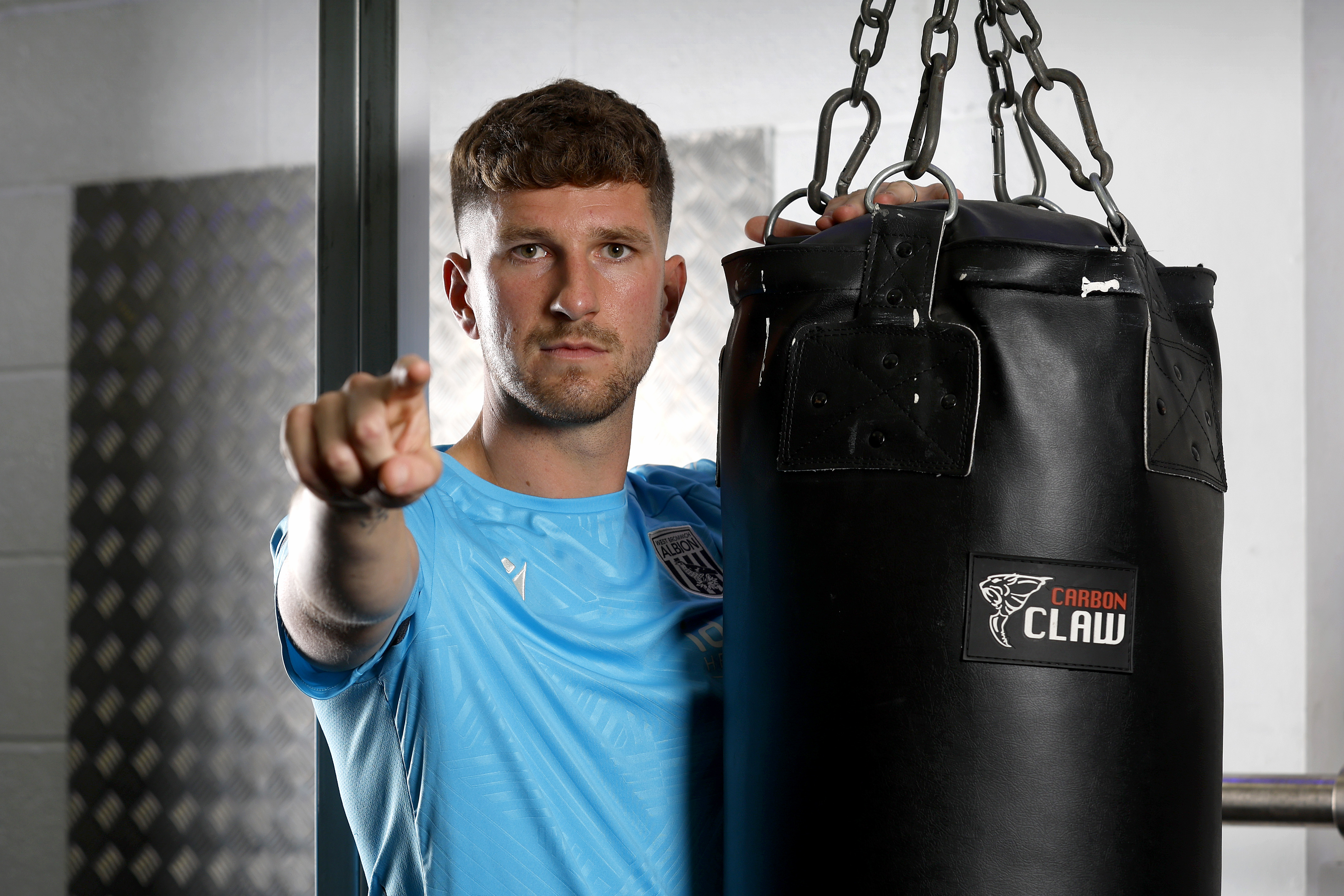 Chris Mepham pointing and looking at the camera while leaning on a punch bag in the gym