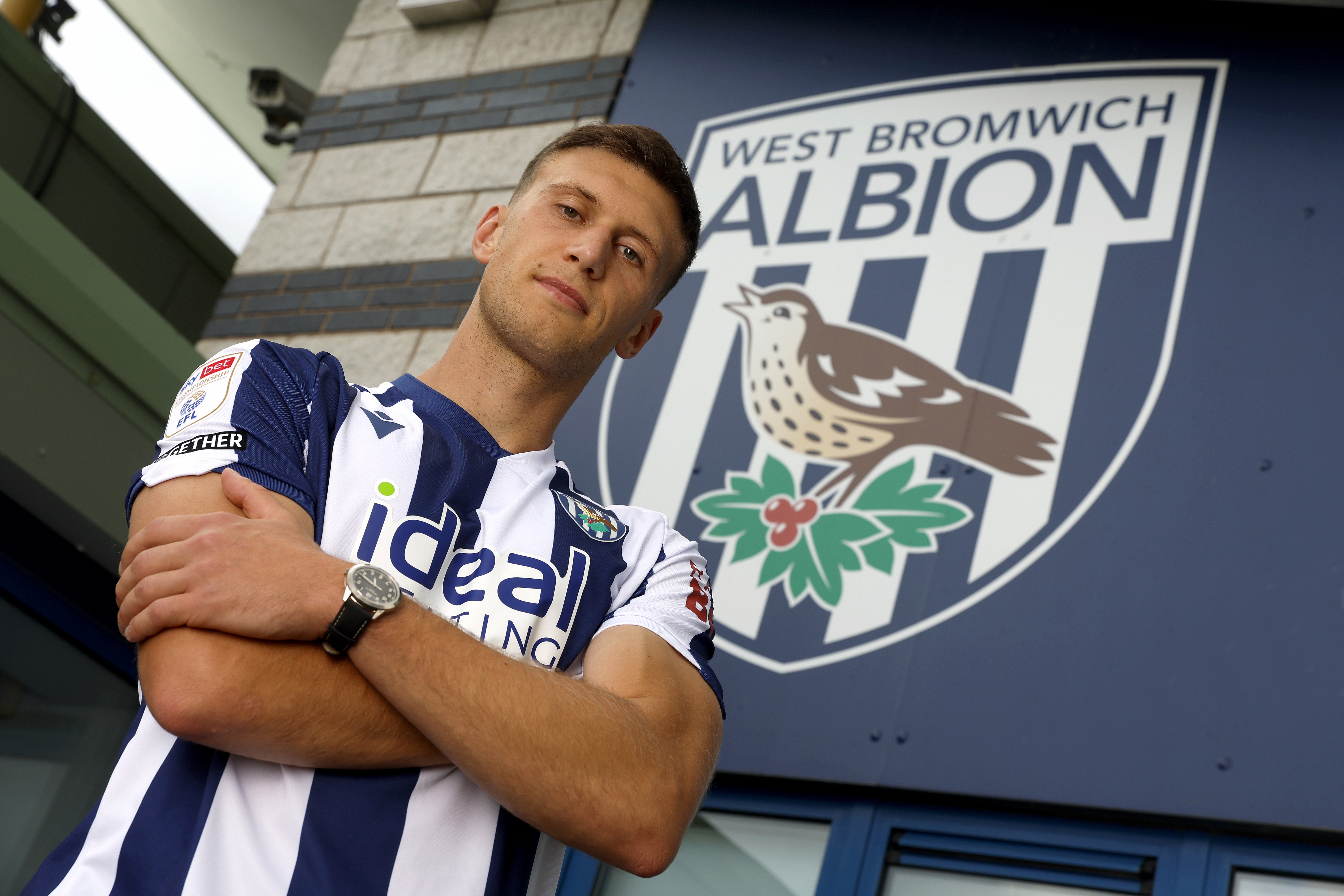 Krystian Bielik looking at the camera while stood in a home shirt with his arms folded