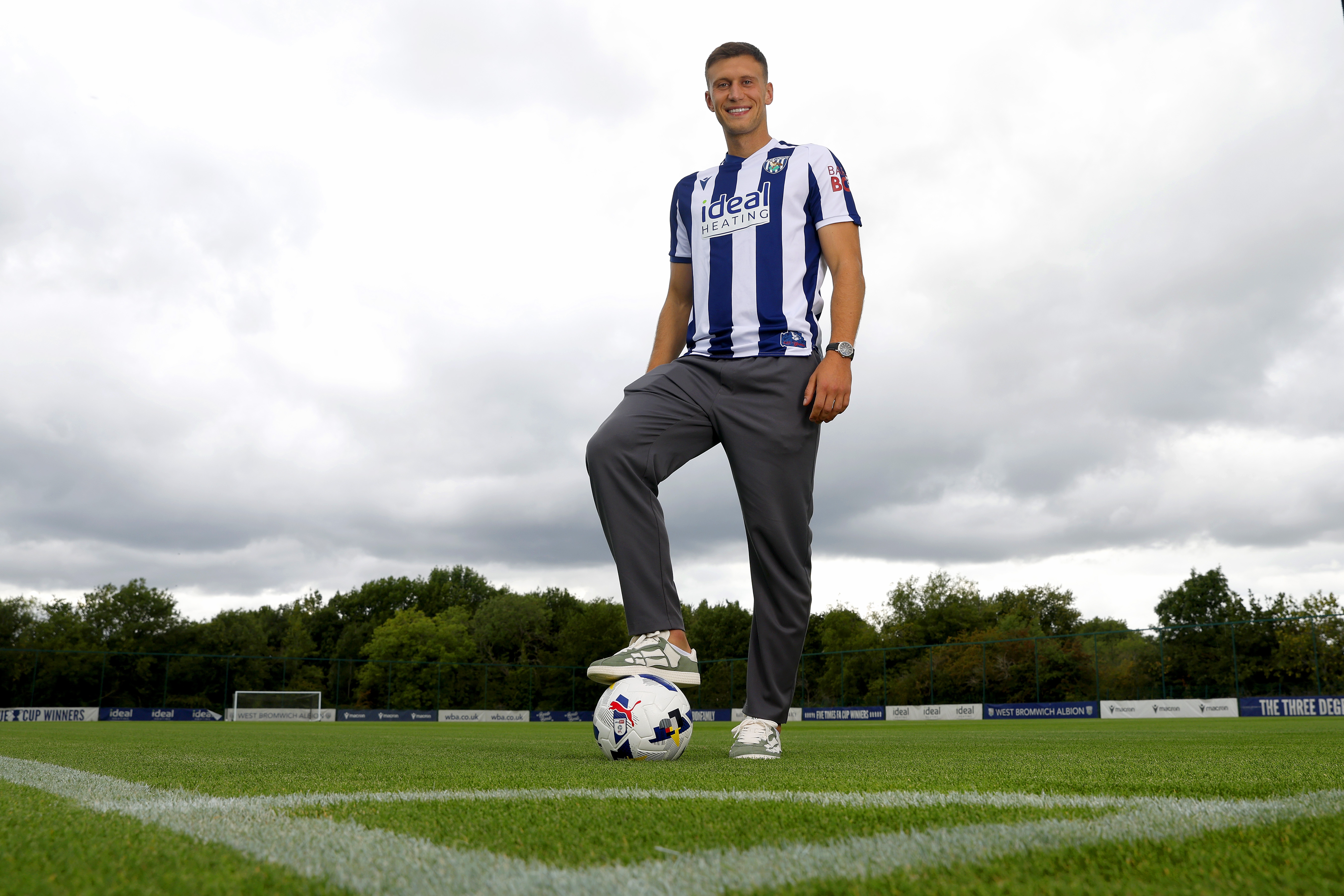 Krystian Bielik smiling at the camera while stood in the home shirt with one foot on the ball
