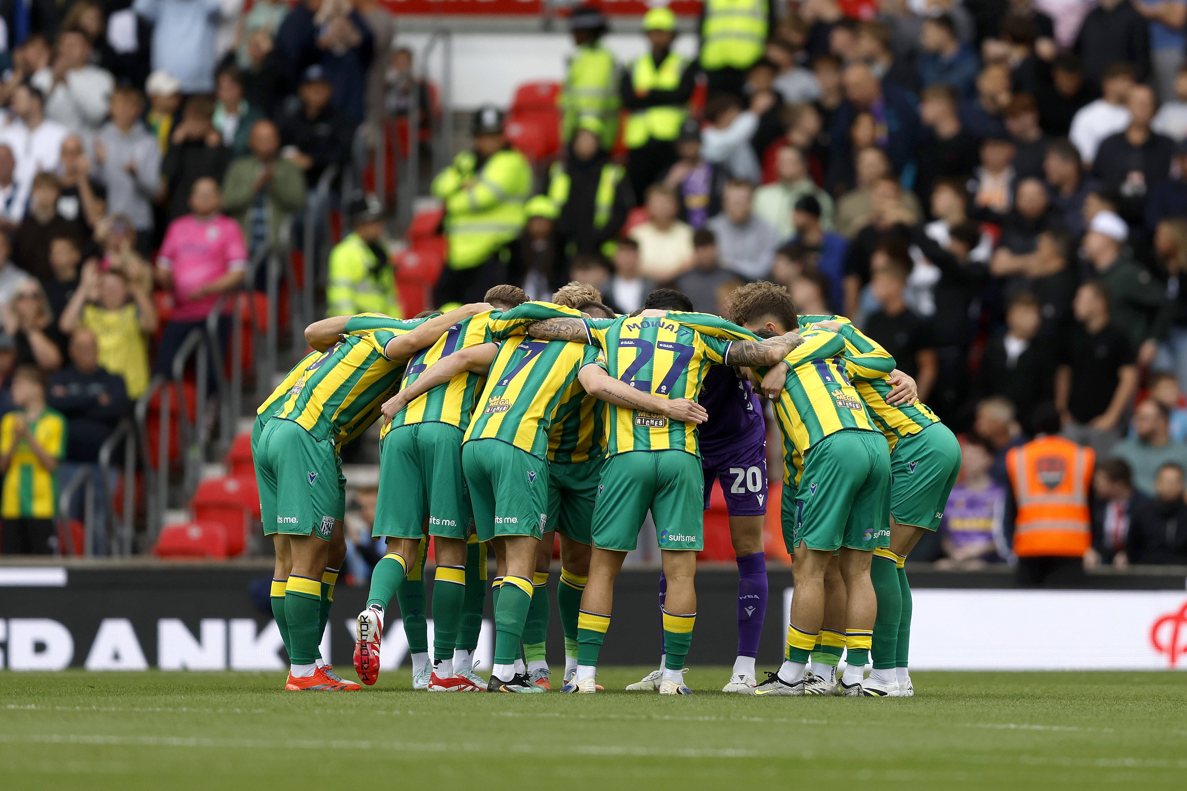 Albion players in the green and yellow away kit in a pre-match huddle before the Stoke game