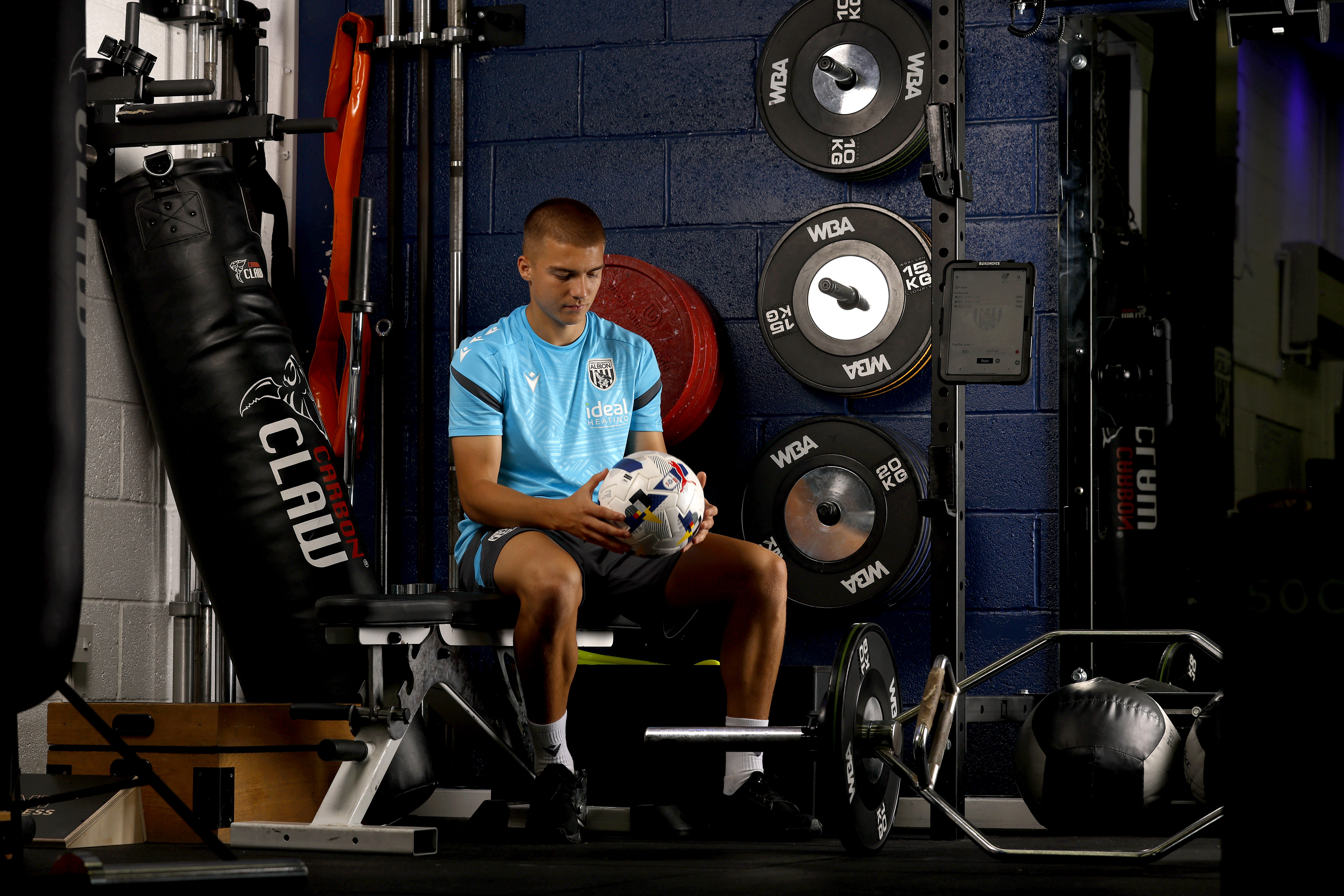 Alfie Gilchrist sat in the gym surrounded by weights holding a ball