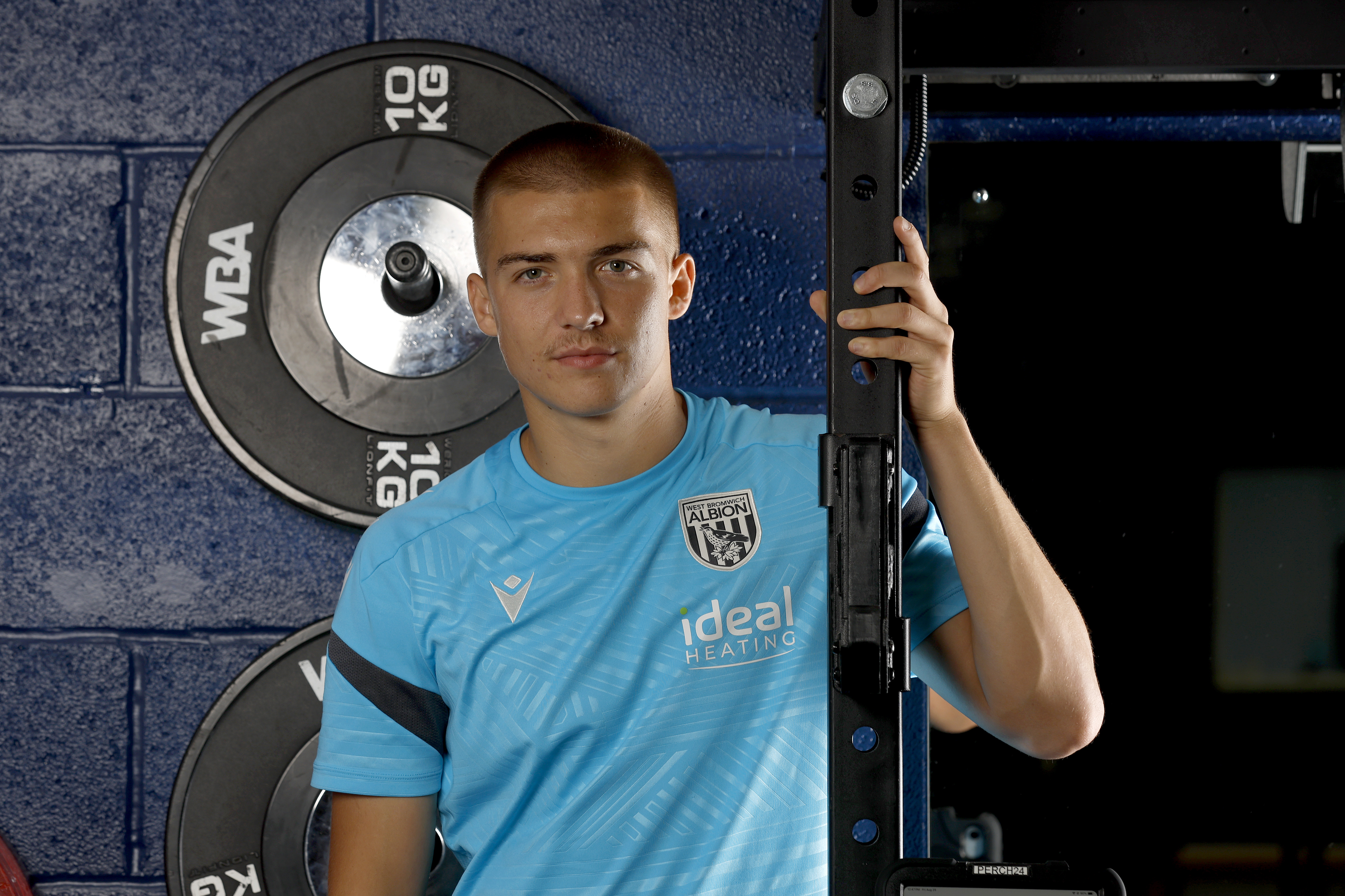 Alfie Gilchrist leaning up against a frame in the gym smiling at the camera 