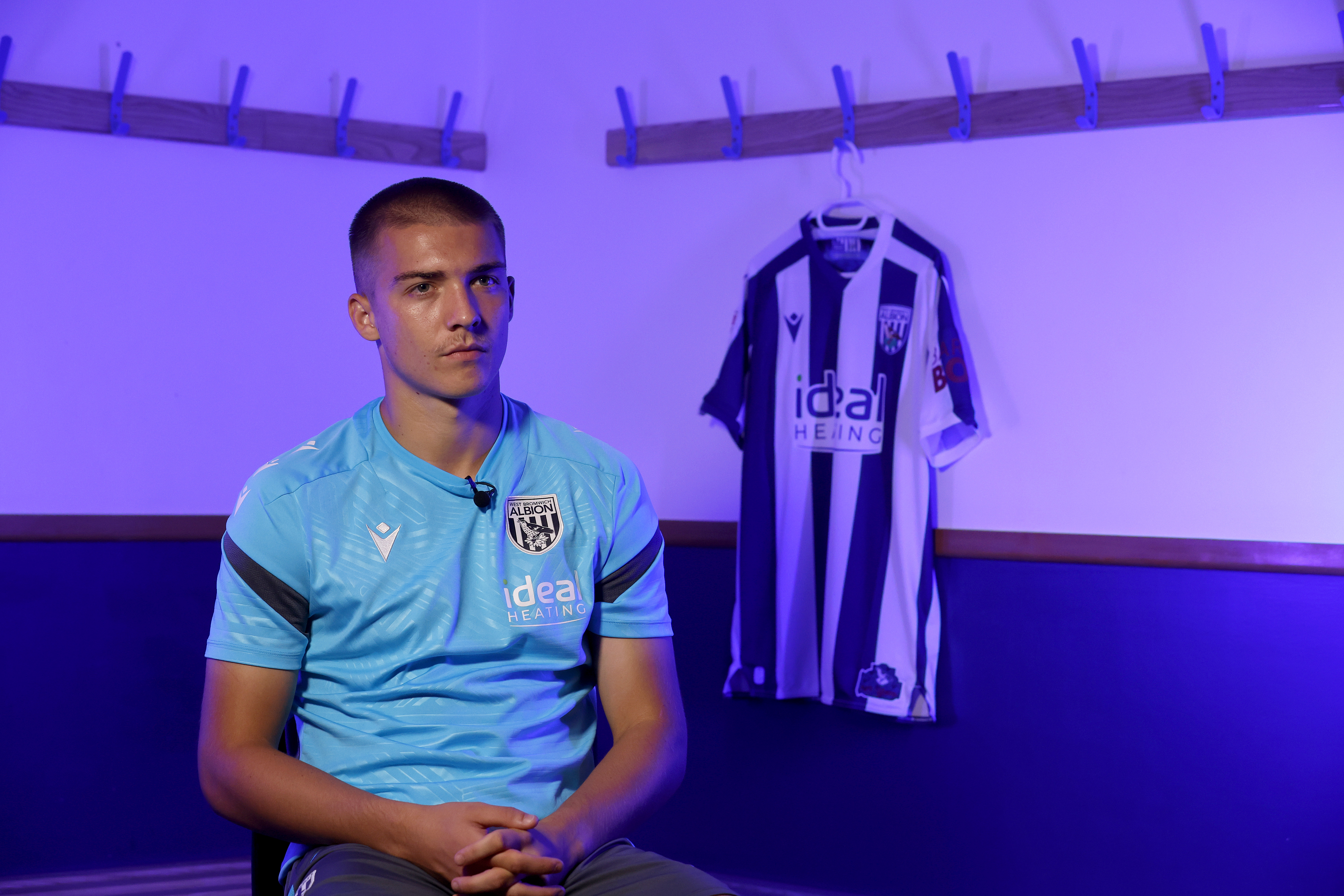 Alfie Gilchrist speaking to WBA TV with a WBA home shirt in the background hanging up
